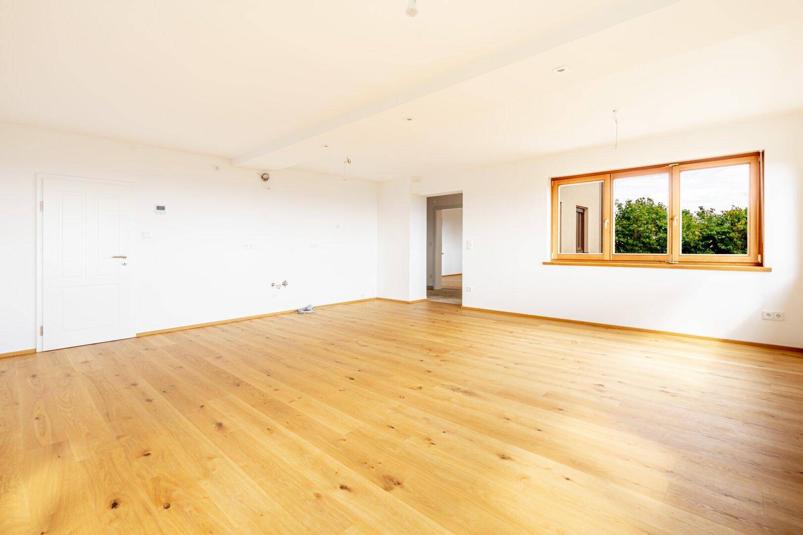 Großer, heller Raum mit Holzboden und Fenstern, der sich ideal für einen offenen Wohnbereich eignet.