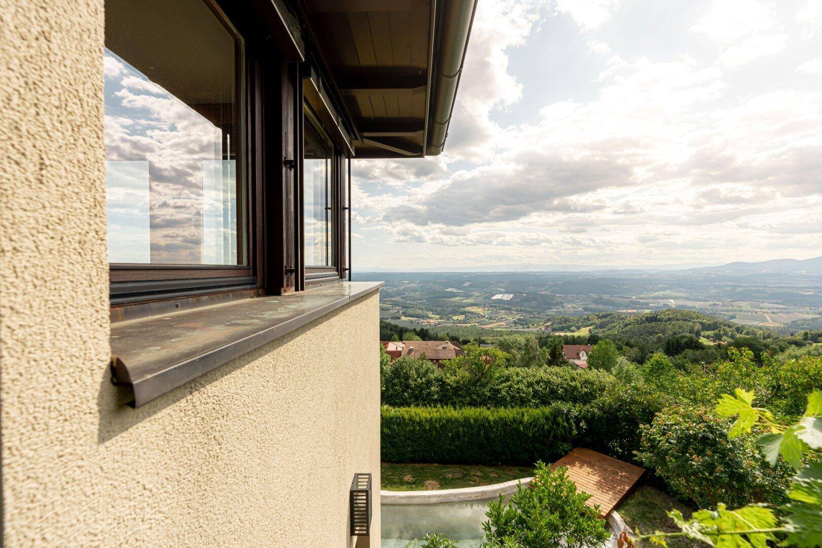 Detailansicht der Fensterfront mit weitem Blick über die hügelige Landschaft und den Garten.