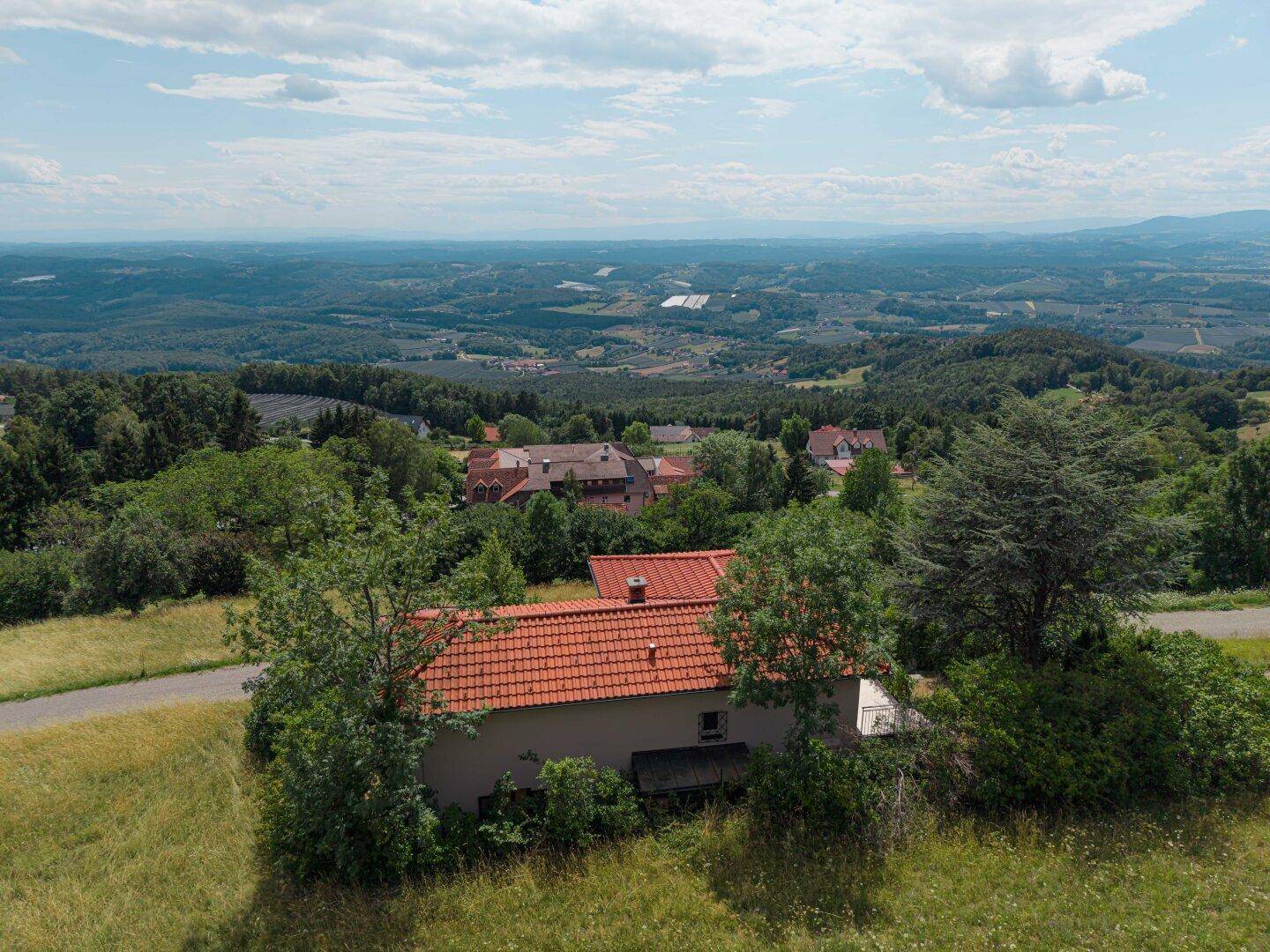 Weitläufige Luftaufnahme eines Hauses in ländlicher Umgebung mit Blick auf ein Tal und weitere Siedlungen.