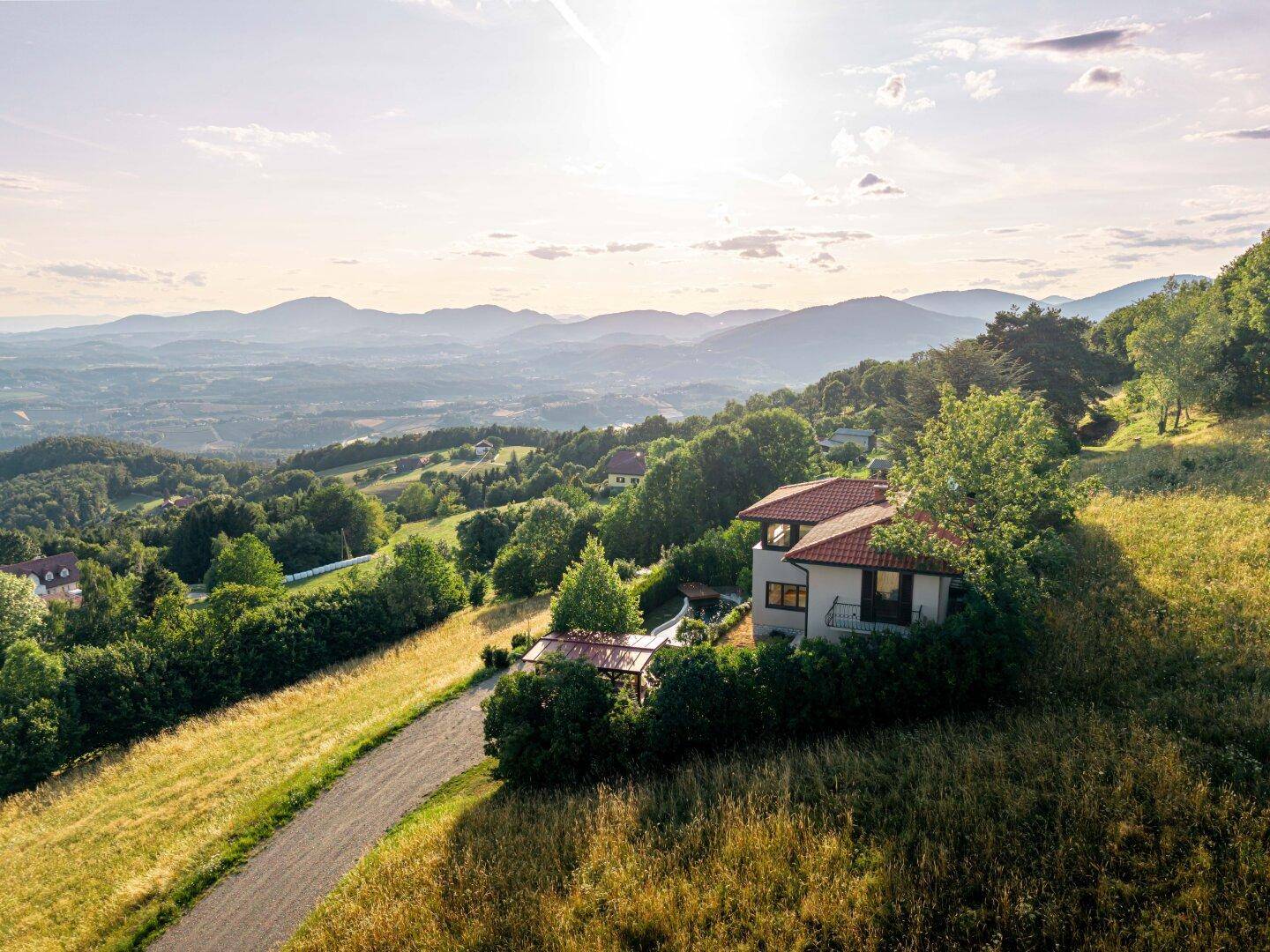 Panoramablick aus der Vogelperspektive auf ein Haus in hügeliger Landschaft mit weitem Horizont.