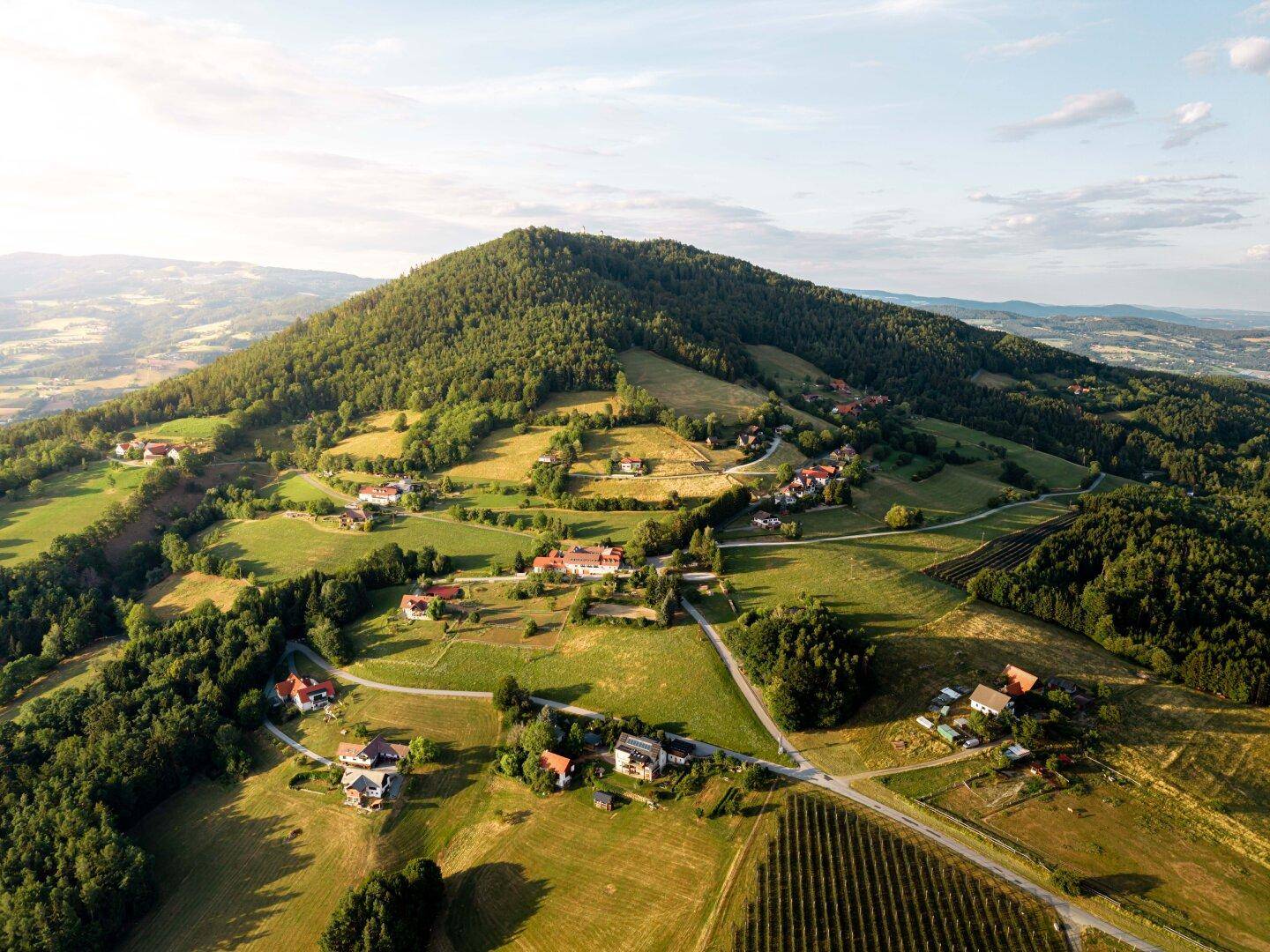 Malerische Luftaufnahme einer ländlichen Gegend mit bewaldeten Hügeln und verstreuten Häusern.