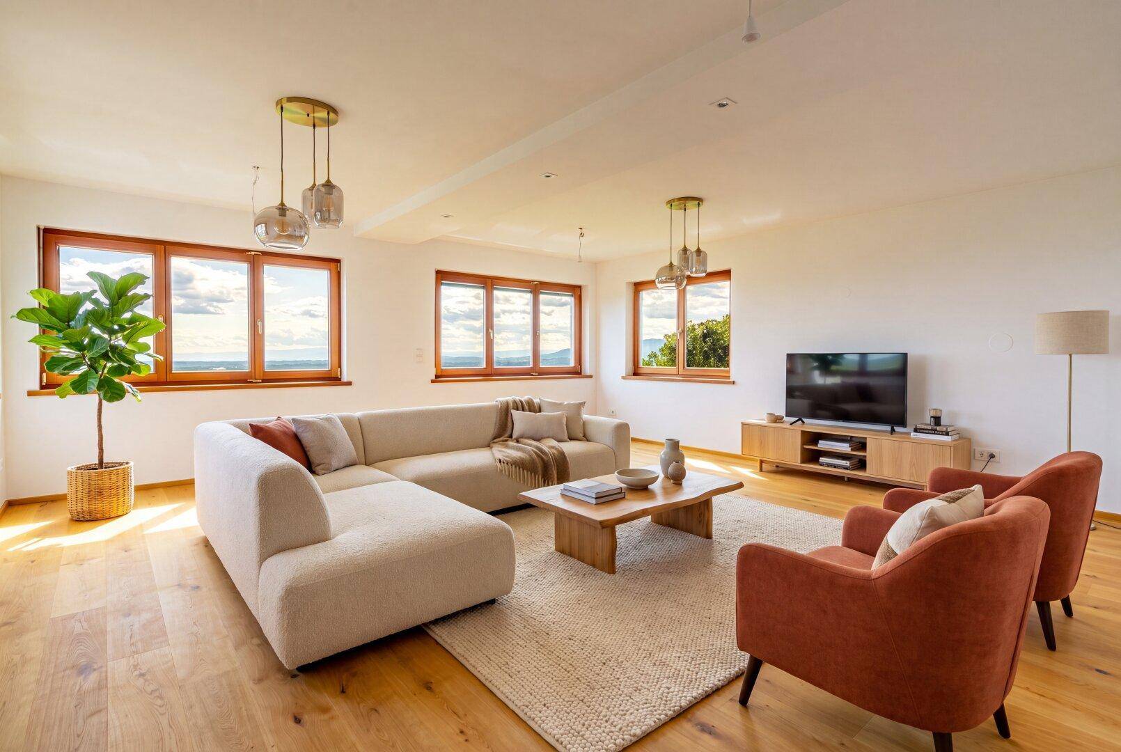 Gemütliches Wohnzimmer mit Holzboden, bequemer Couch und großen Fenstern mit weitem Ausblick.