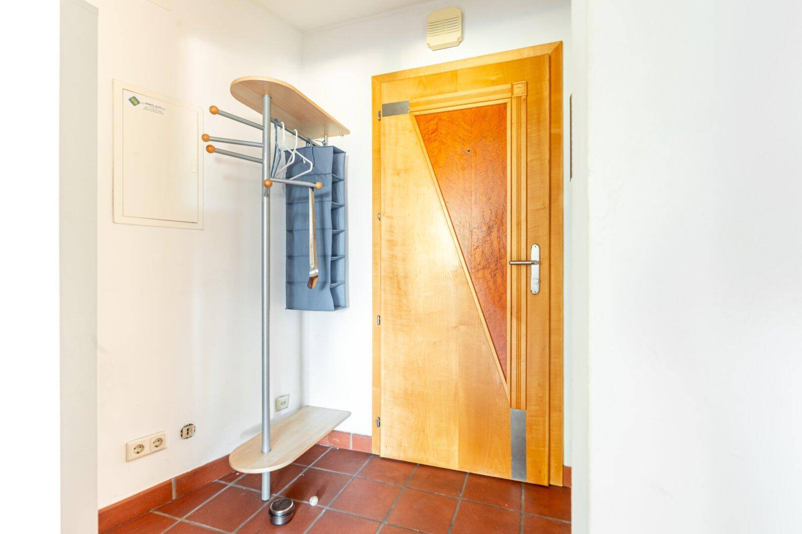 Eingangsbereich mit Terrakotta-Fliesenboden und moderner Garderobe, einladend und funktional gestaltet.