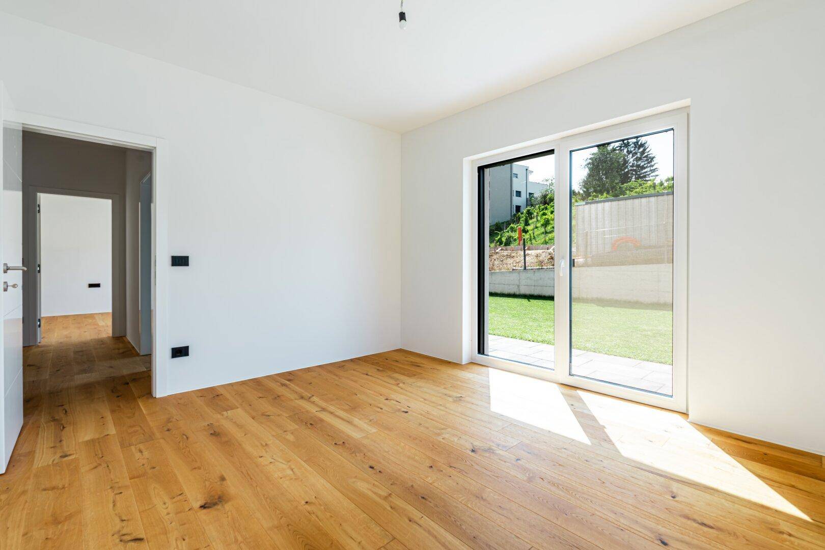 Heller Raum mit Holzboden und großer Schiebetür zum Garten, ideal als Schlaf- oder Arbeitszimmer.