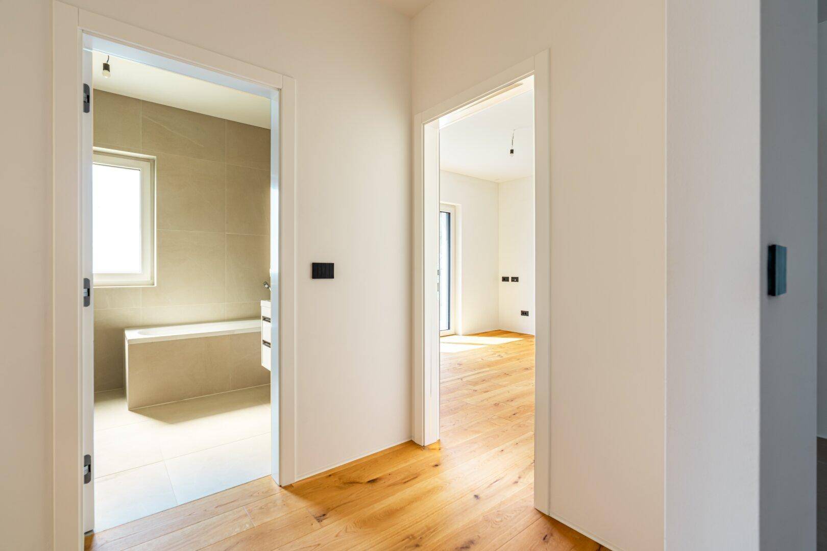 Heller Flur mit Holzboden, der den Zugang zu einem Badezimmer und einem weiteren Zimmer ermöglicht.
