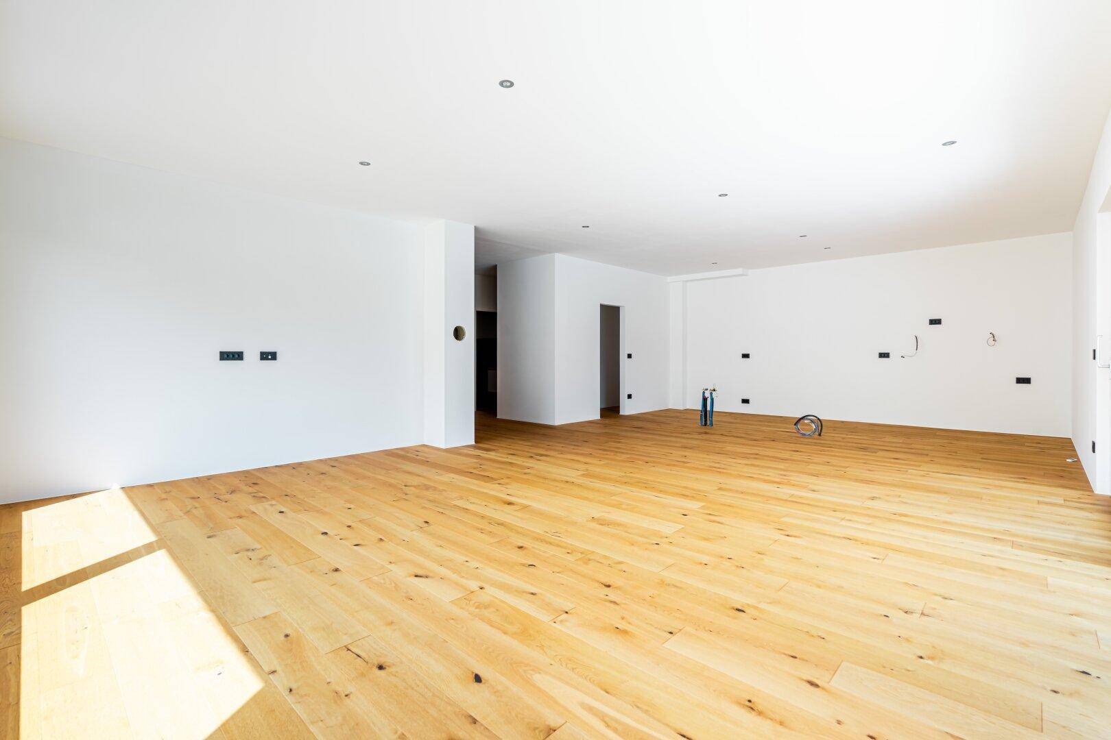 Weitläufiger, heller Raum mit Holzboden, ideal für einen offenen Wohn- und Essbereich.