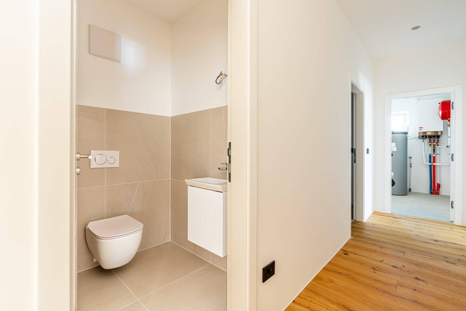 Modernes Gäste-WC mit Wand-WC und kleinem Waschbecken, angrenzend an einen Technikraum.