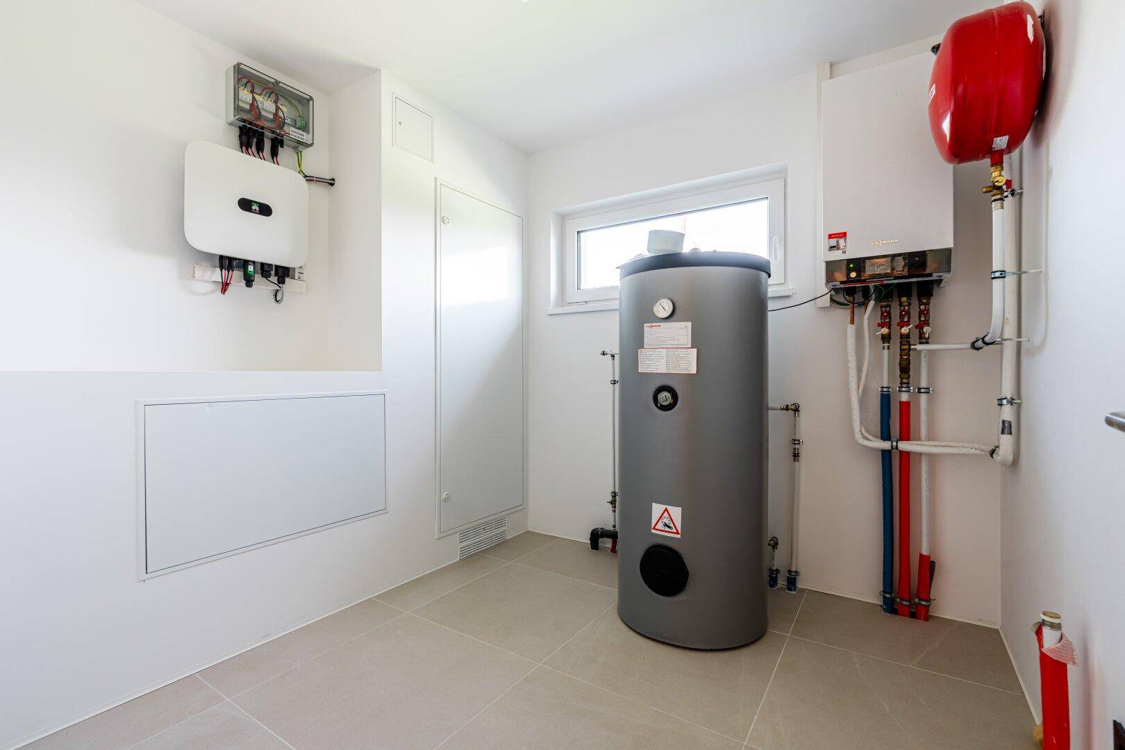 Technikraum mit Warmwasserspeicher, Heizungsanlage und Photovoltaik-Steuerung.