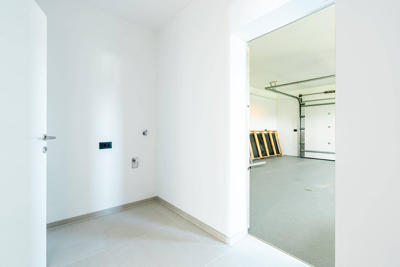 Heller Hauswirtschaftsraum mit Fliesenboden und Zugang zur Garage.