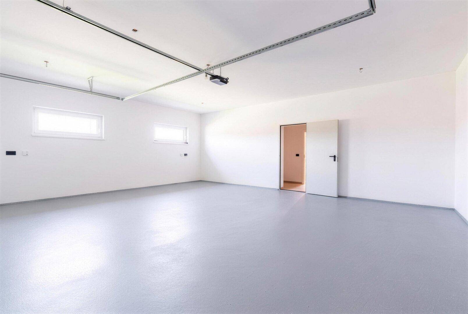 Große, helle Garage mit zwei Fenstern und direktem Zugang zum Haus.