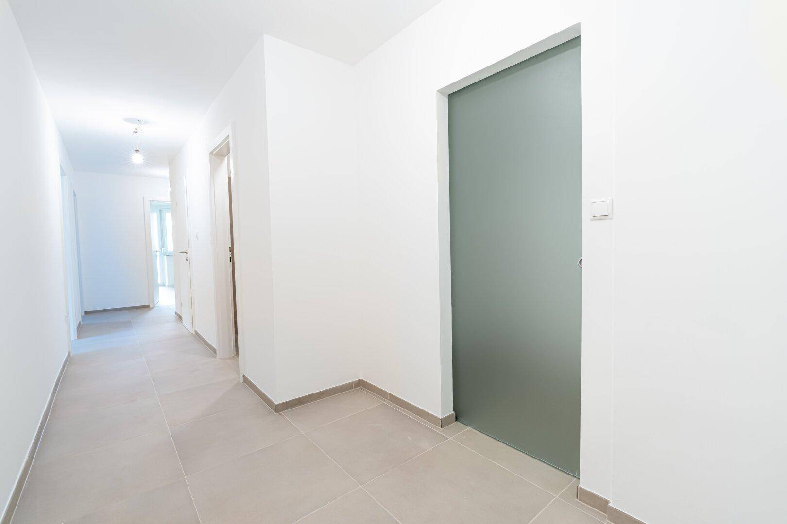Moderner Flur mit Fliesenboden und einer eleganten Schiebetür aus satiniertem Glas.