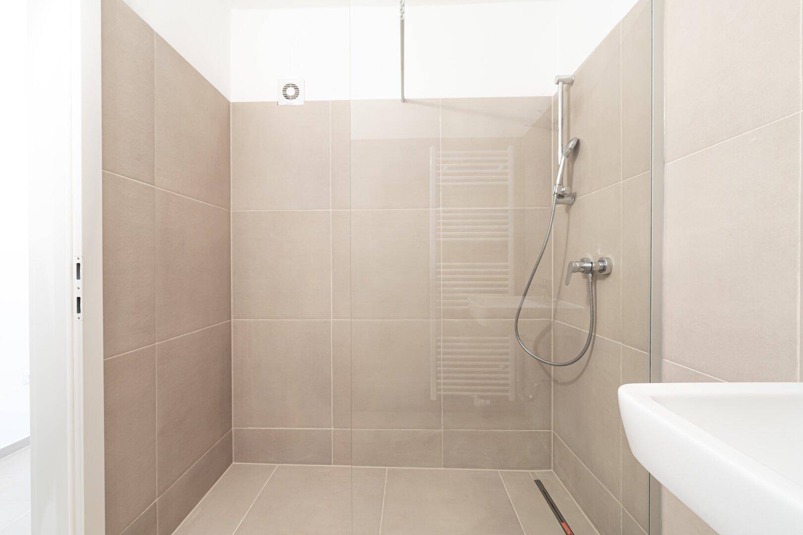 Unmöbliertes, modernes Badezimmer mit ebenerdiger Dusche und Fliesenboden.