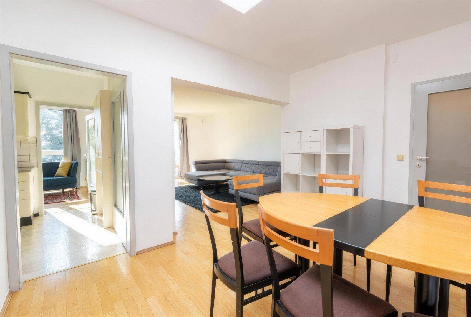 Essbereich mit Holzboden und offenem Zugang zum Wohnzimmer durch eine Glastür.