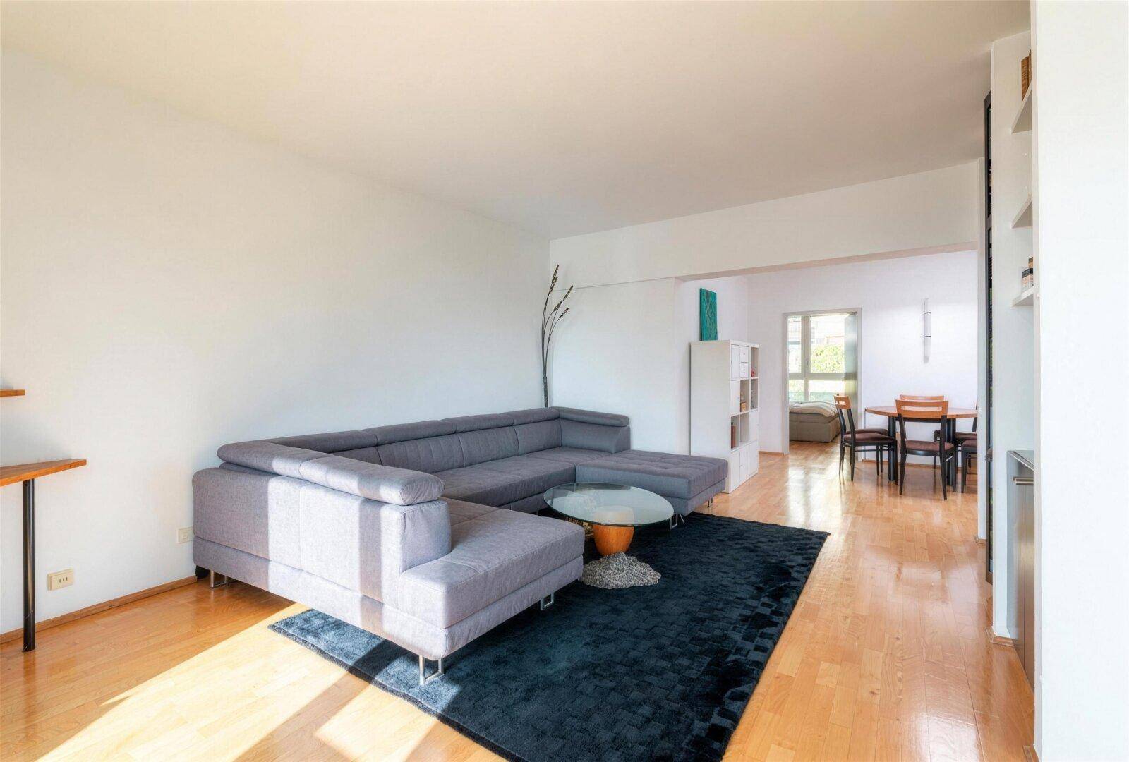 Geräumiges Wohnzimmer mit großem Ecksofa, Holzboden und Blick auf den Essbereich.