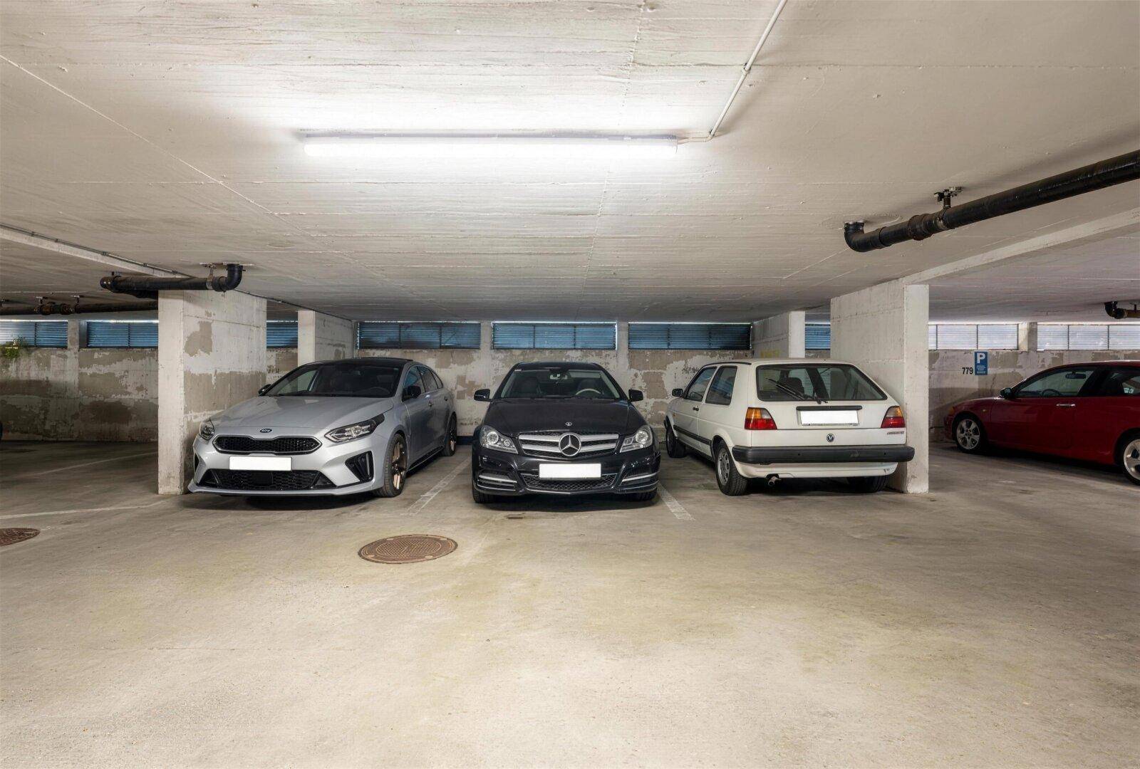 Tiefgarage mit mehreren geparkten Fahrzeugen und Betonwänden.