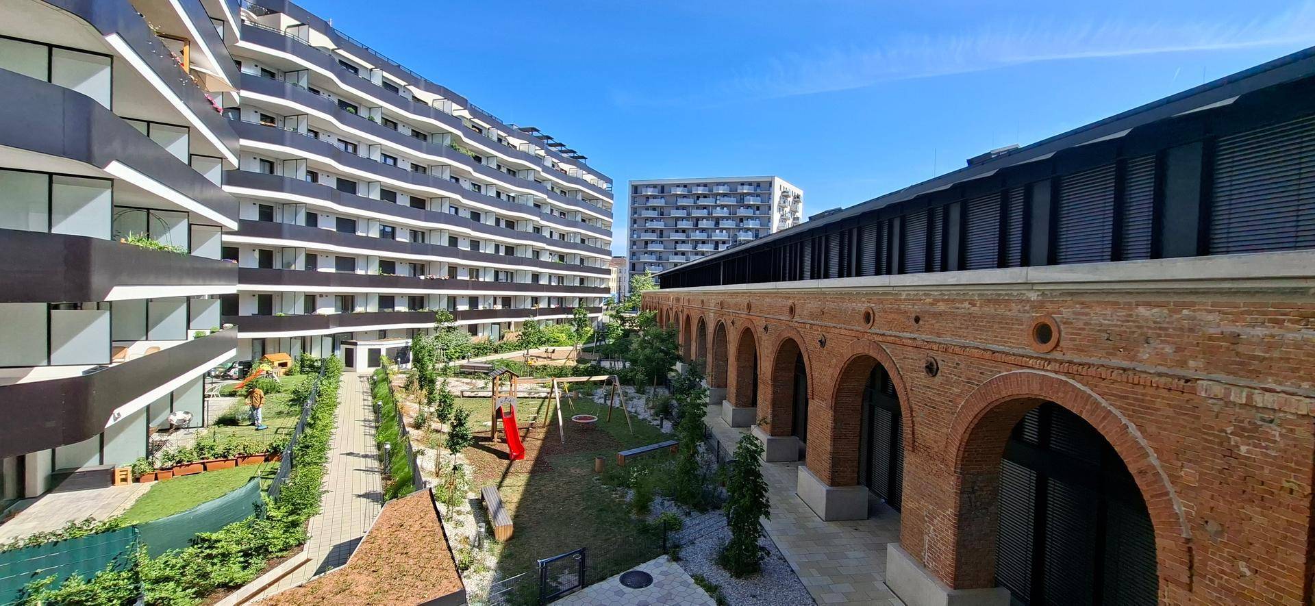 Innenhof mit Spielplatz, umgeben von modernen Wohngebäuden und historischer Backsteinarchitektur.