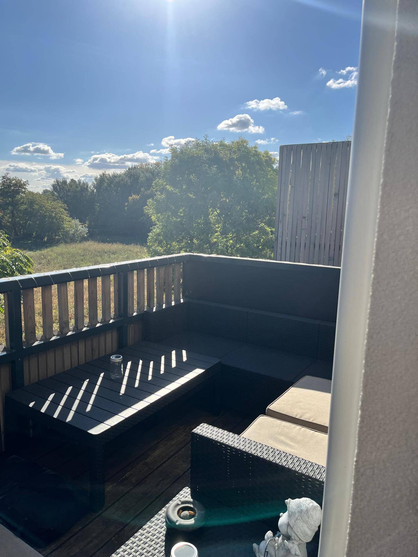 Sonniger Balkon mit gemütlichen Loungemöbeln und Blick ins Grüne.
