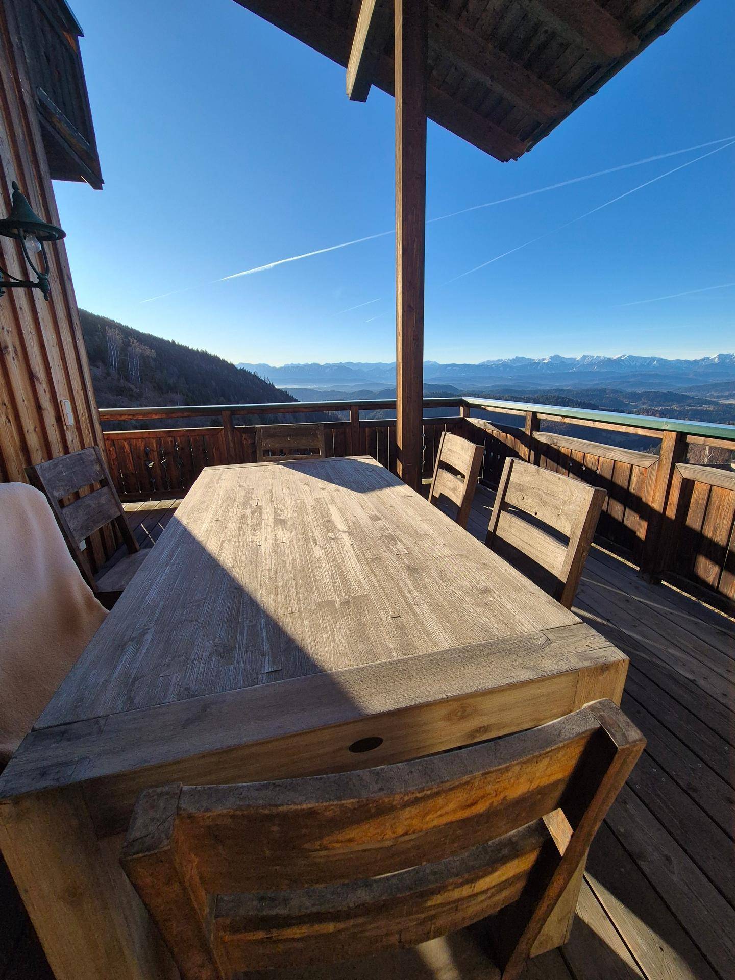 Gemütliche Holzterrasse mit Esstisch und Stühlen, bietet einen atemberaubenden Panoramablick.
