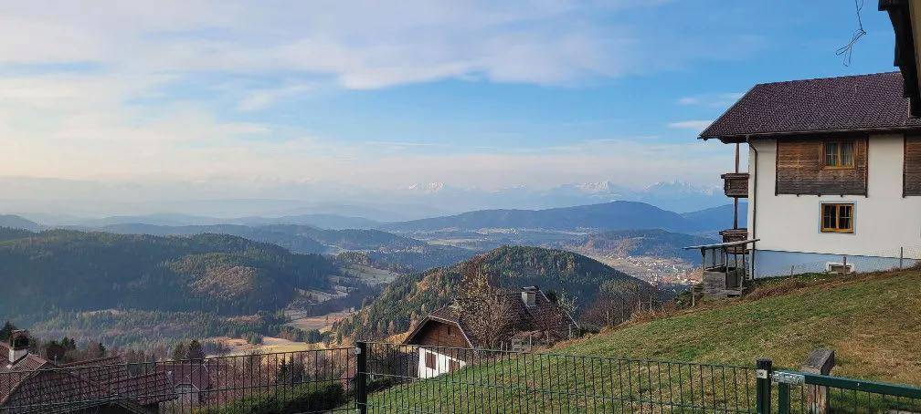 Hausfassade mit weitem Blick über eine hügelige Landschaft und ferne Berge.