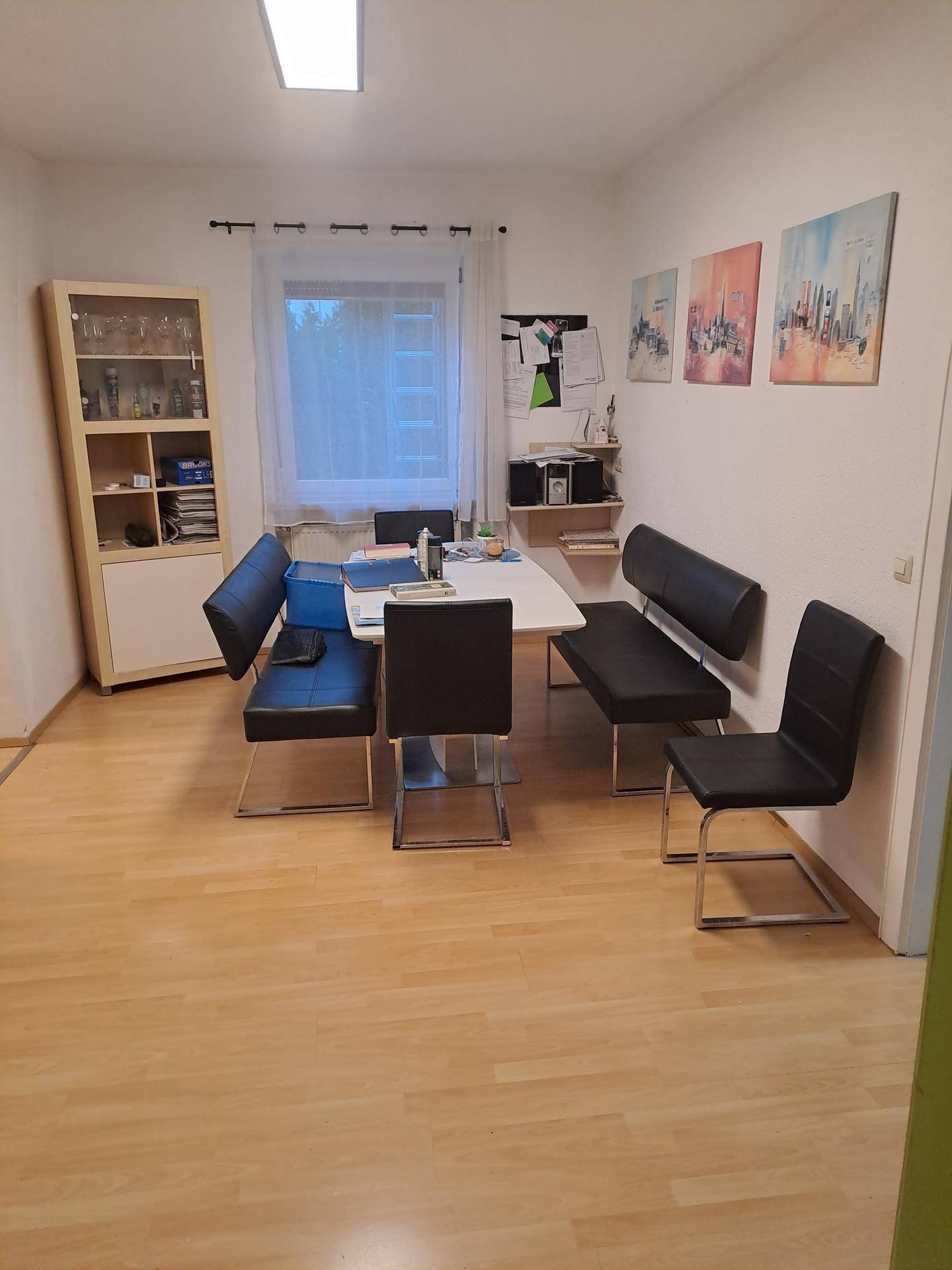 Esszimmer mit hellem Laminatboden, Esstisch und Sitzbänken, dekoriert mit Bildern.
