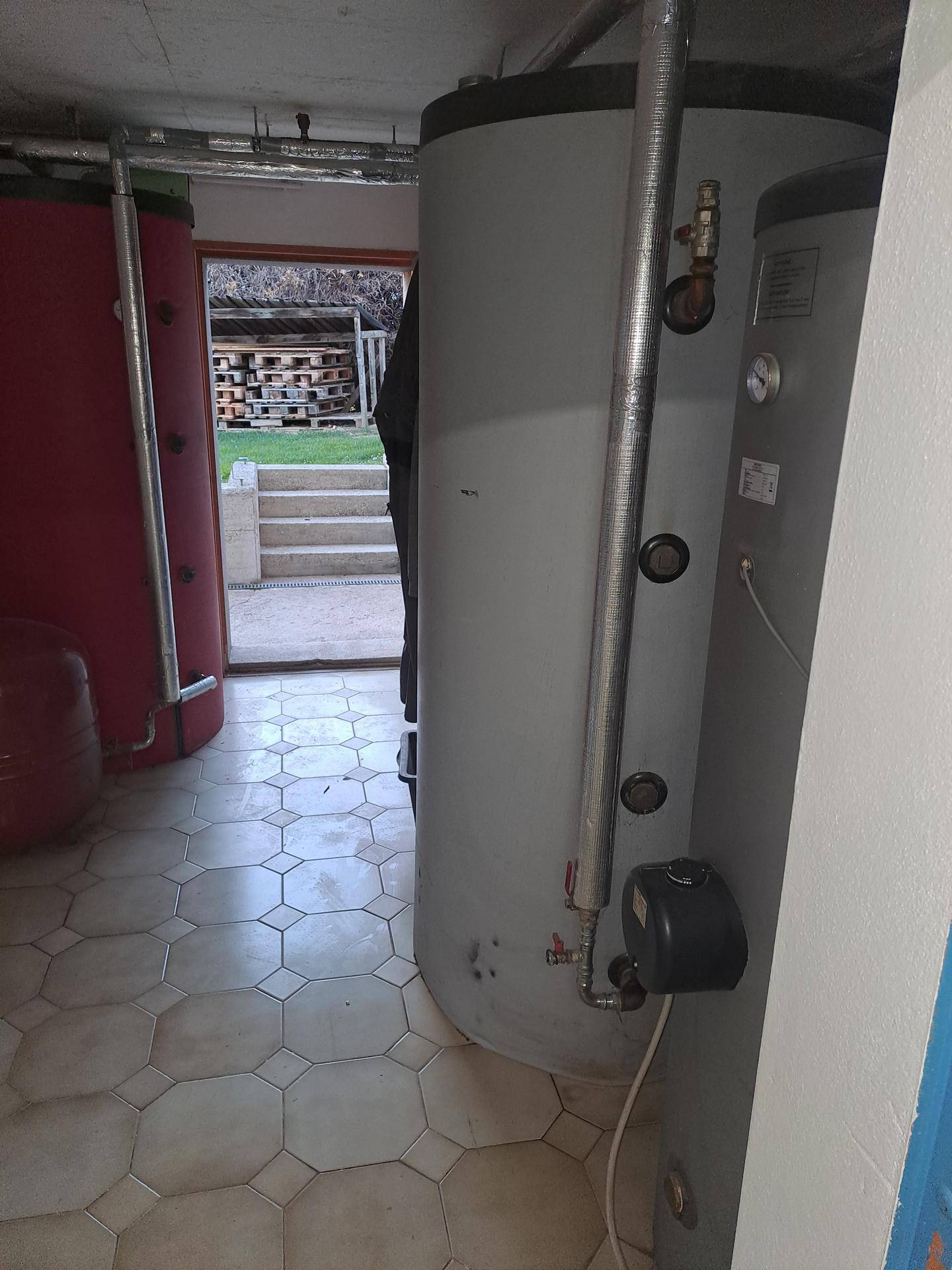 Technikraum mit großen Warmwasserspeichern und Zugang zum Außenbereich.