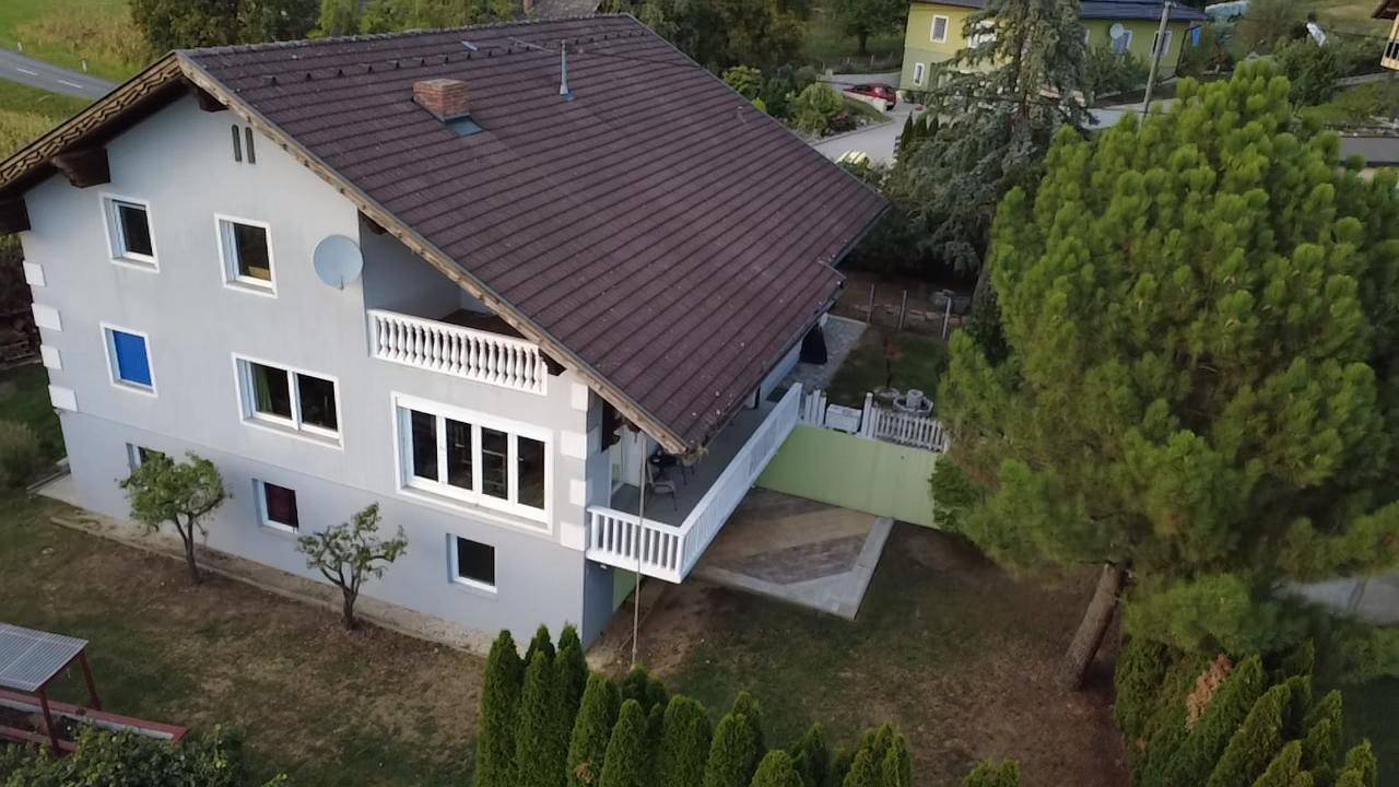 Nahaufnahme eines Einfamilienhauses mit Balkonen und einem gepflegten Gartenbereich.