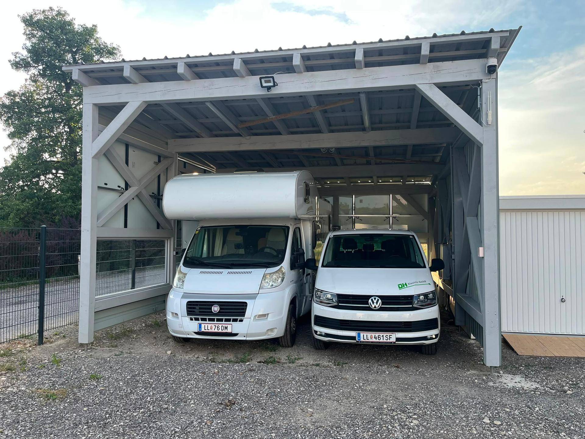 Geräumiger Carport mit Holzbalkenkonstruktion und Überwachungskamera für zwei Fahrzeuge.
