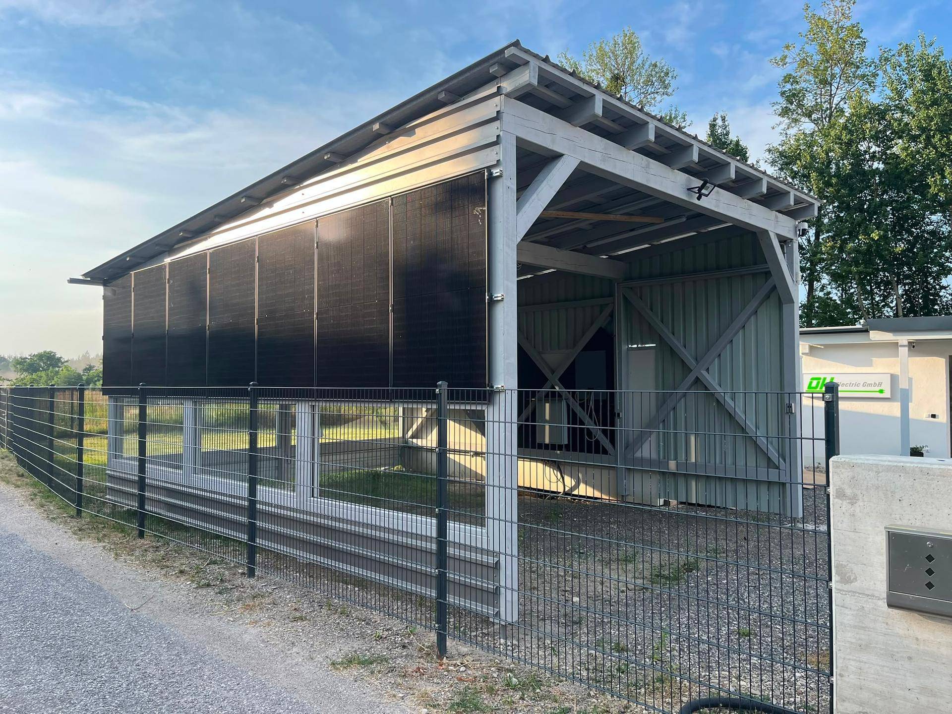 Seitenansicht des Carports mit integrierten Solarmodulen und einem Metallzaun.