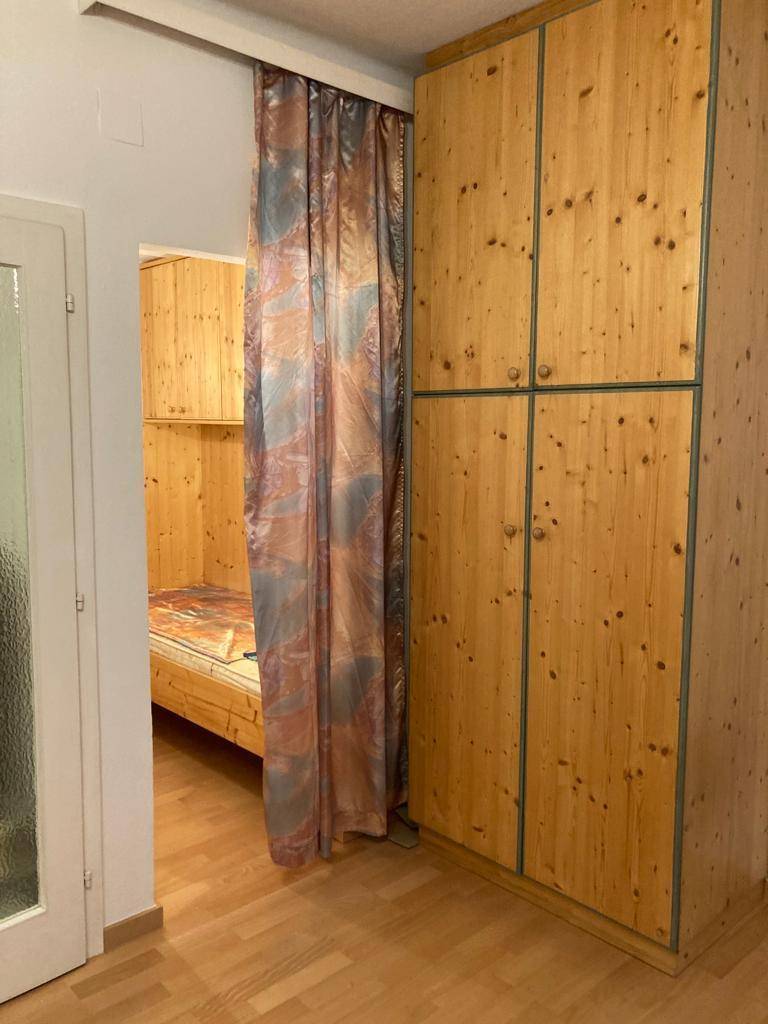 Schlafbereich mit integriertem Bett in einer Nische und großem Holzschrank.