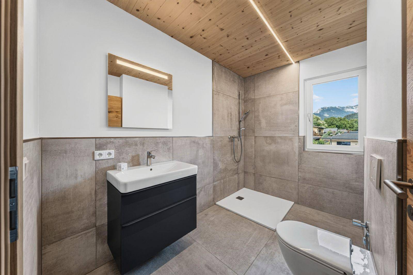 Modernes Badezimmer mit begehbarer Dusche, schwebendem Waschtisch und Fenster mit Bergblick.
