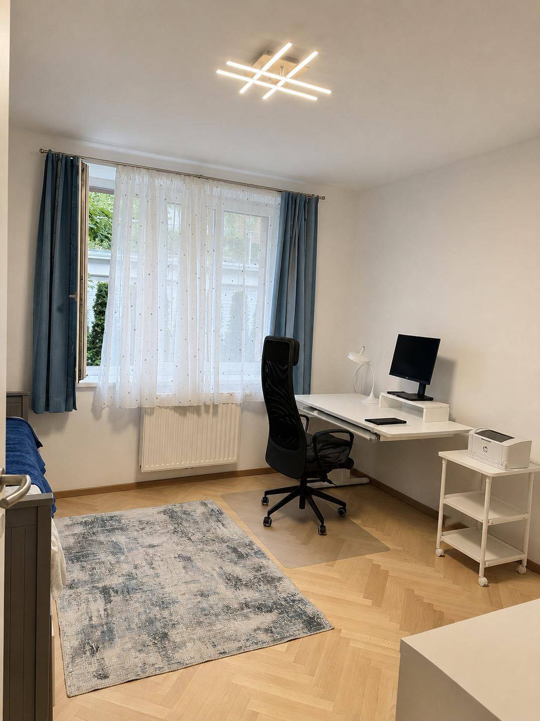 Helles Arbeitszimmer mit Parkettboden, großem Fenster und modernem Schreibtisch für produktives Arbeiten.