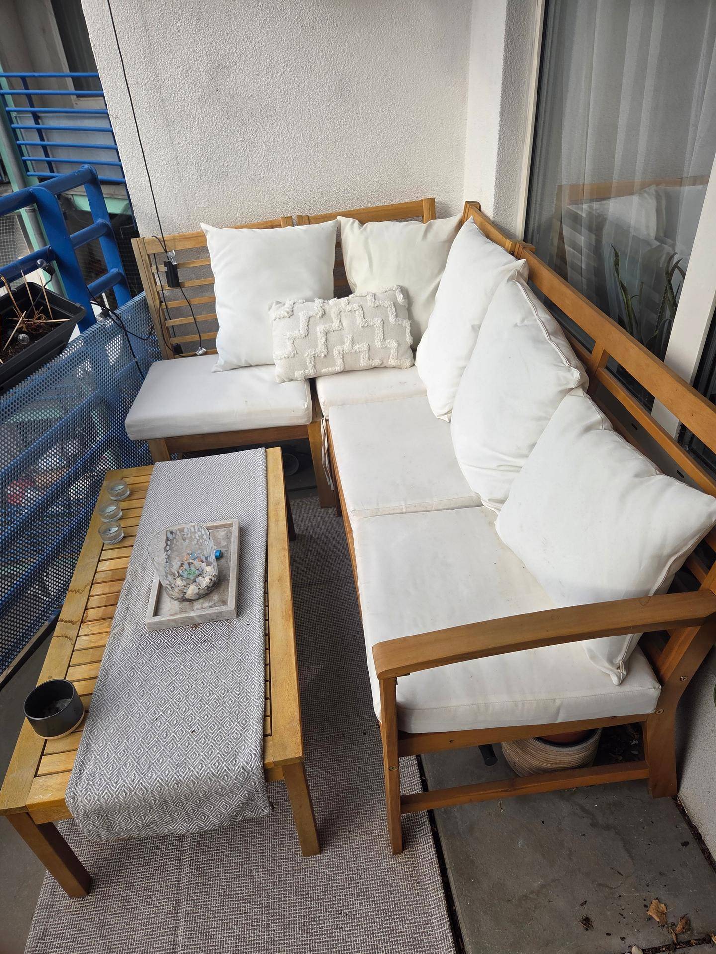 Möblierter Balkon mit Holzsitzgruppe und weißen Kissen, perfekt für entspannte Stunden im Freien.