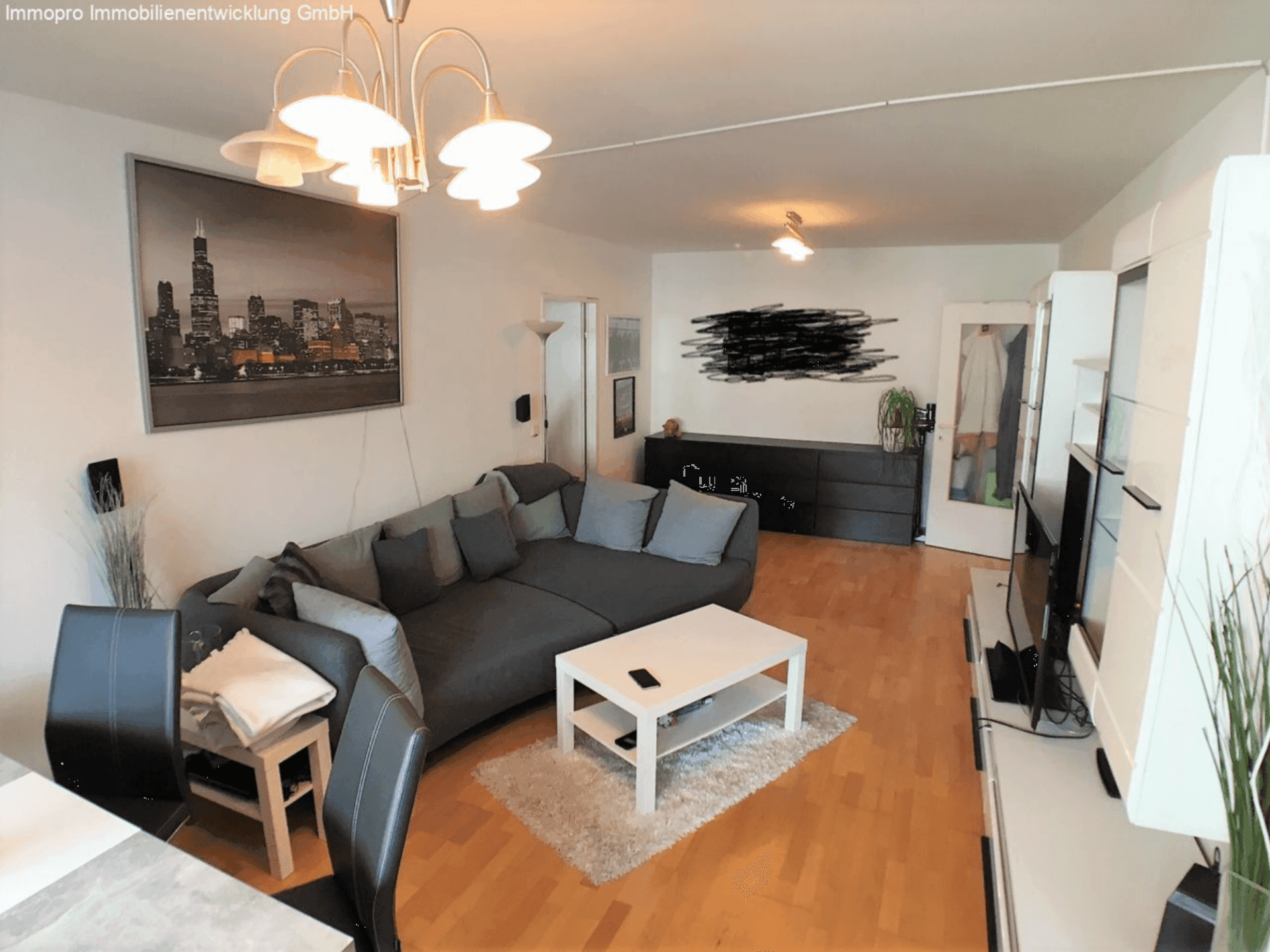 Gemütliches Wohnzimmer mit großem Sofa, Holzboden und moderner Dekoration, ideal zum Entspannen.