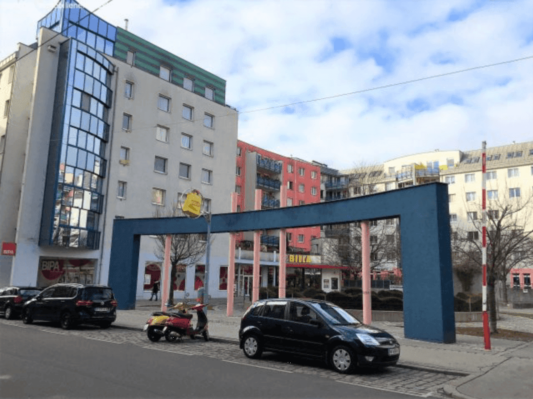 Moderne Wohngebäude mit Glasfassaden und Geschäften im Erdgeschoss an einer städtischen Straße.