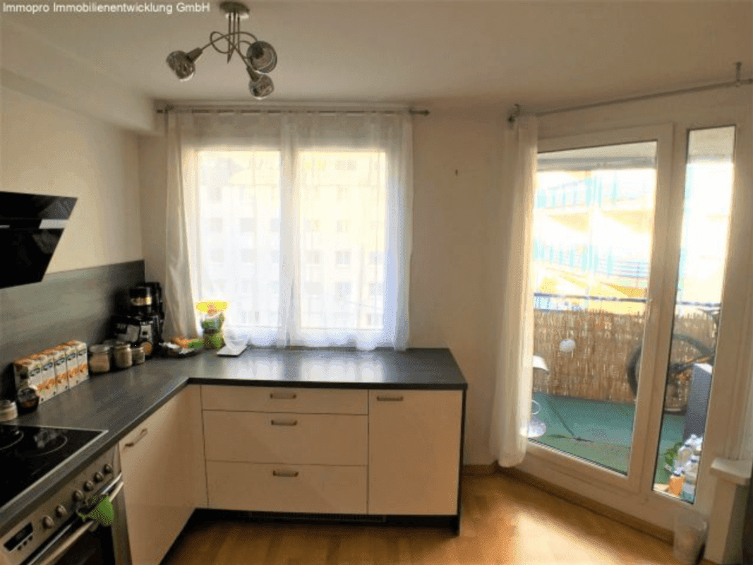 Helle Küche mit Fenster und Zugang zu einem kleinen Balkon, der viel Tageslicht hereinlässt.