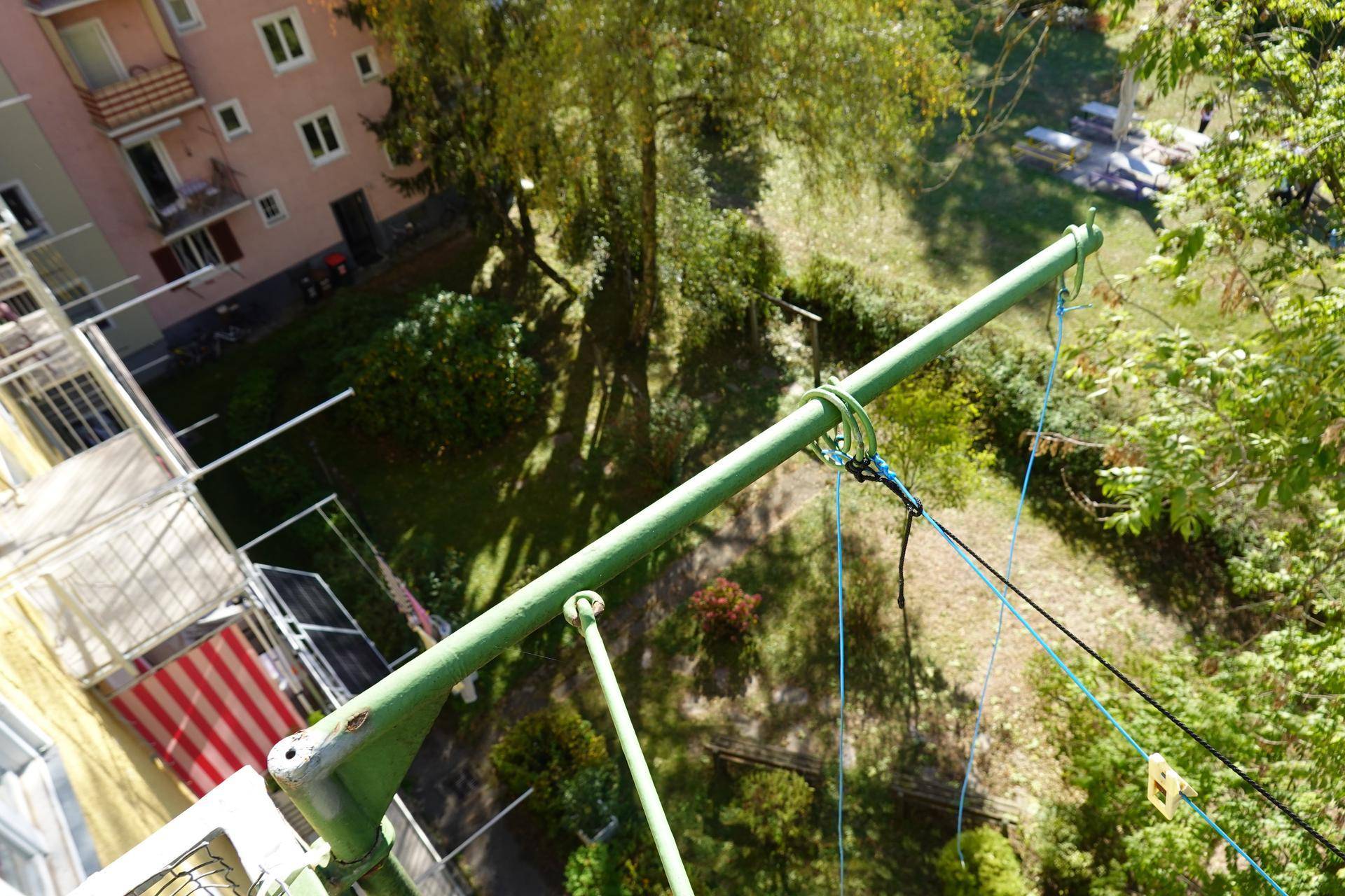 Blick vom Balkon nach unten auf den Innenhof mit Wäscheleinen und umliegenden Gebäuden.