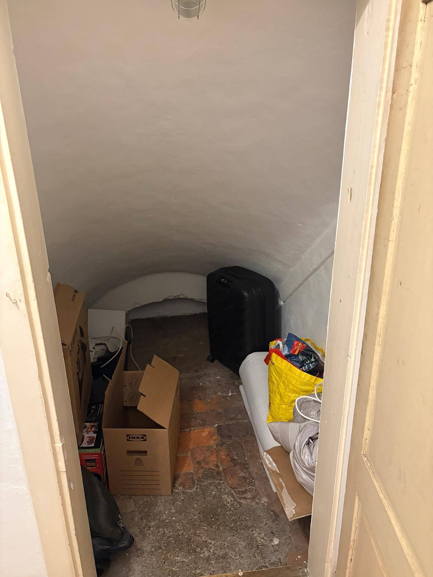 Kleiner Abstellraum mit gewölbter Decke, gefüllt mit Kartons und Gepäck.