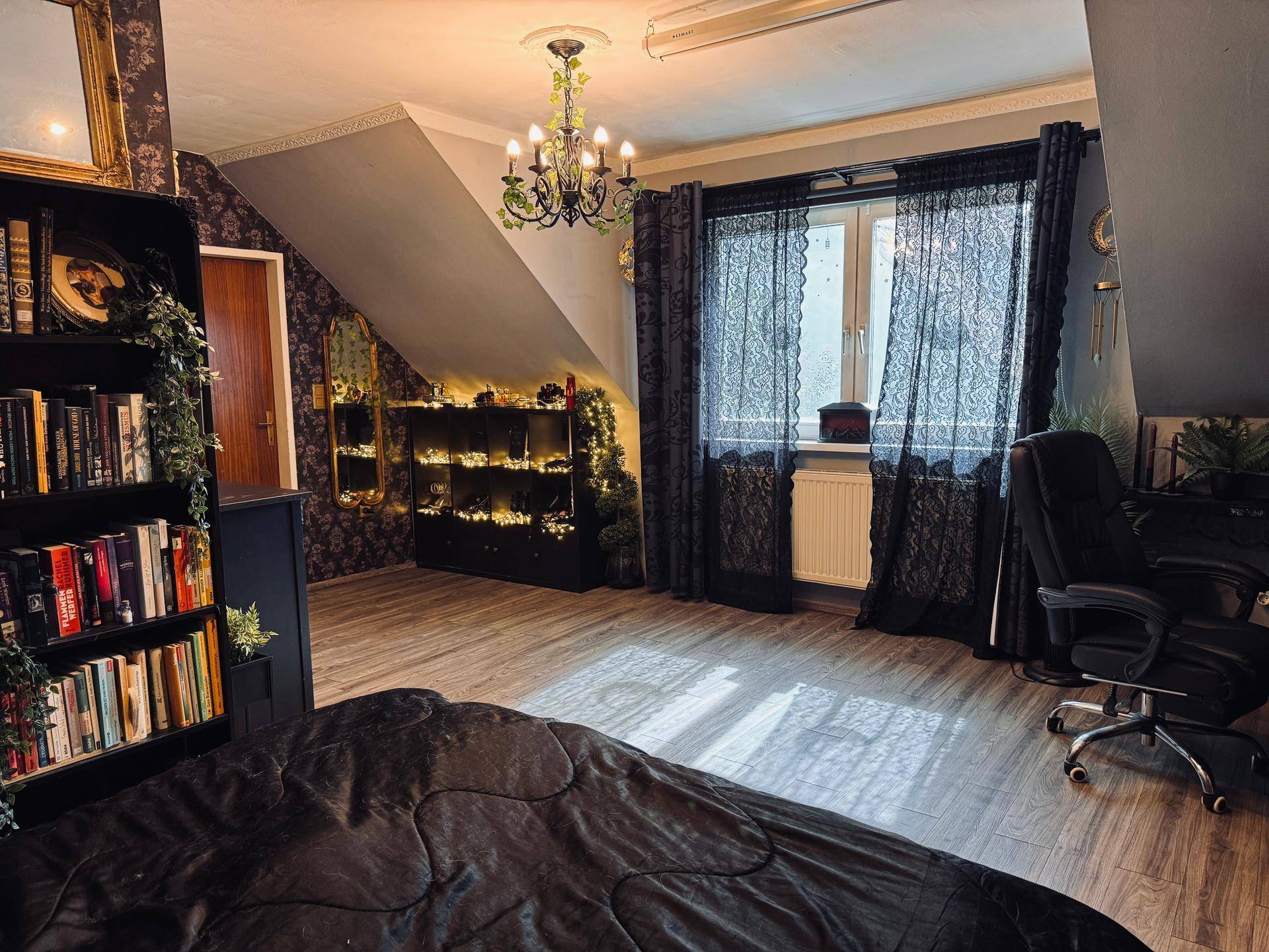 Schlafzimmer im Dachgeschoss mit dunkler Einrichtung, Bücherregal und Fenster mit blickdichten Vorhängen.