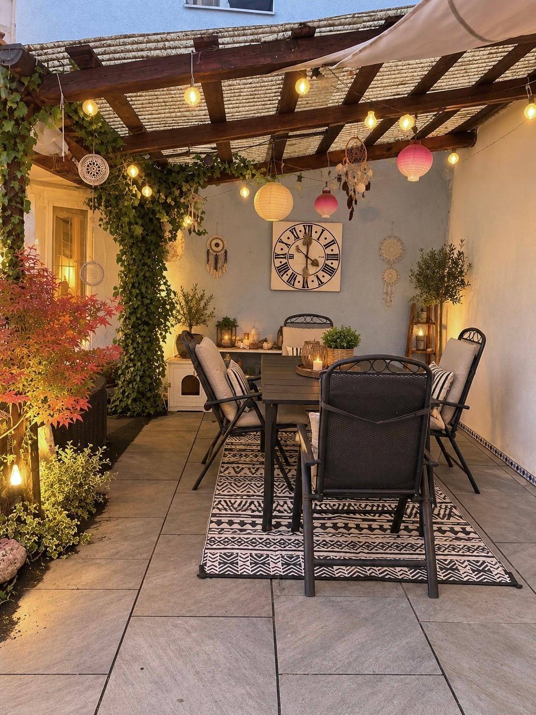 Gemütliche Terrasse mit Esstisch, Lichterketten und dekorativen Laternen für entspannte Abende.