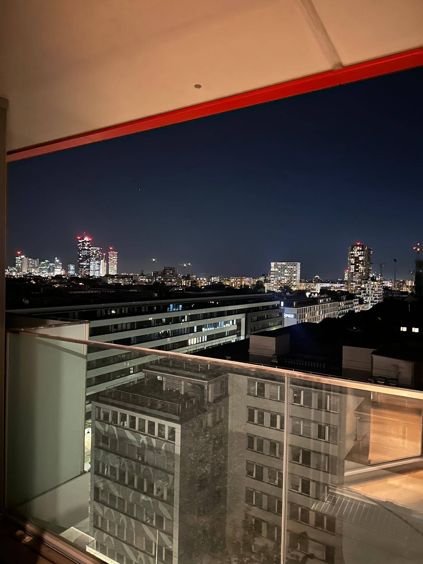 Balkon bei Nacht mit beeindruckendem Blick auf die beleuchtete Stadt und ihre Skyline.