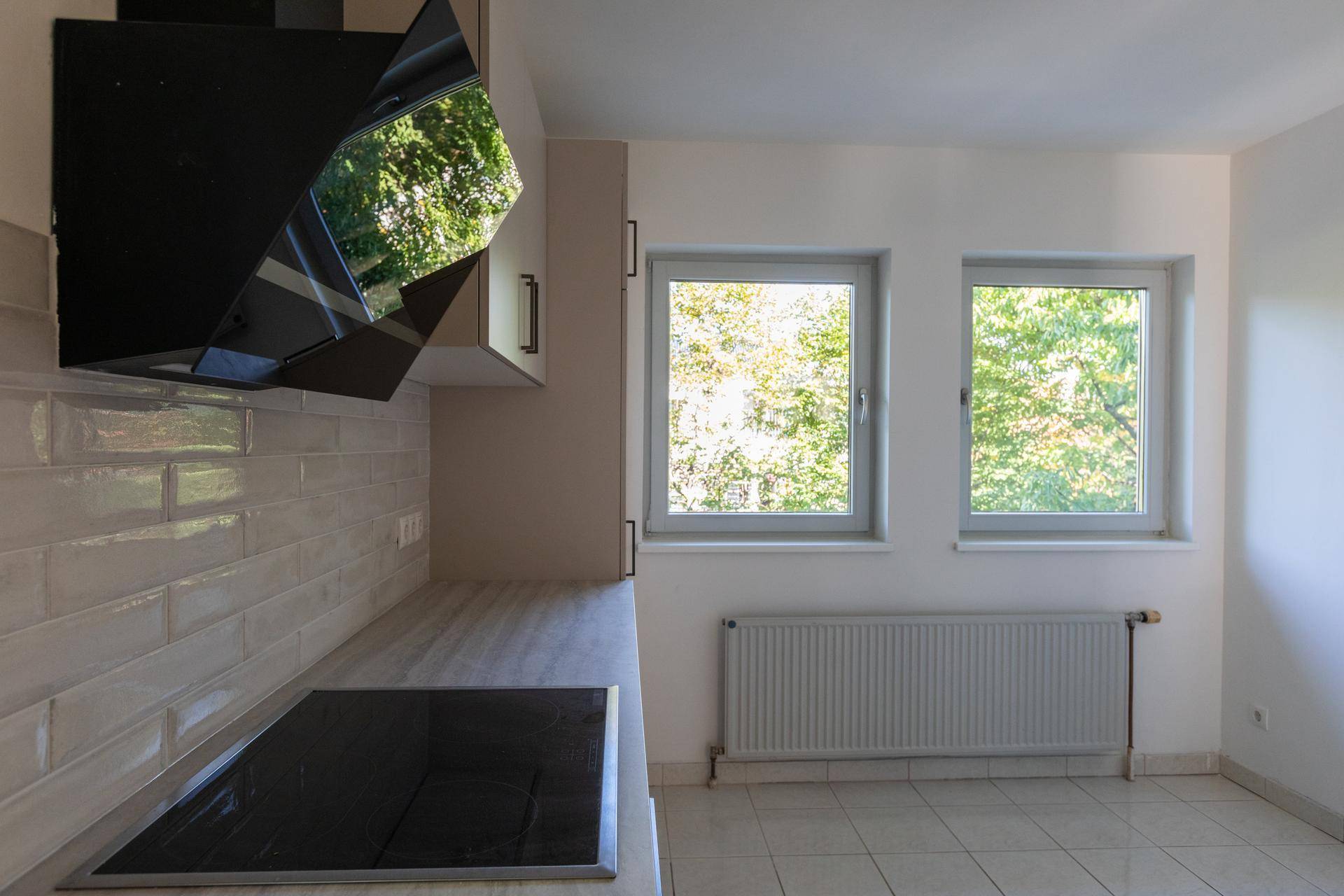 Funktionale Küche mit Induktionskochfeld, Dunstabzugshaube und zwei Fenstern für natürliches Licht.