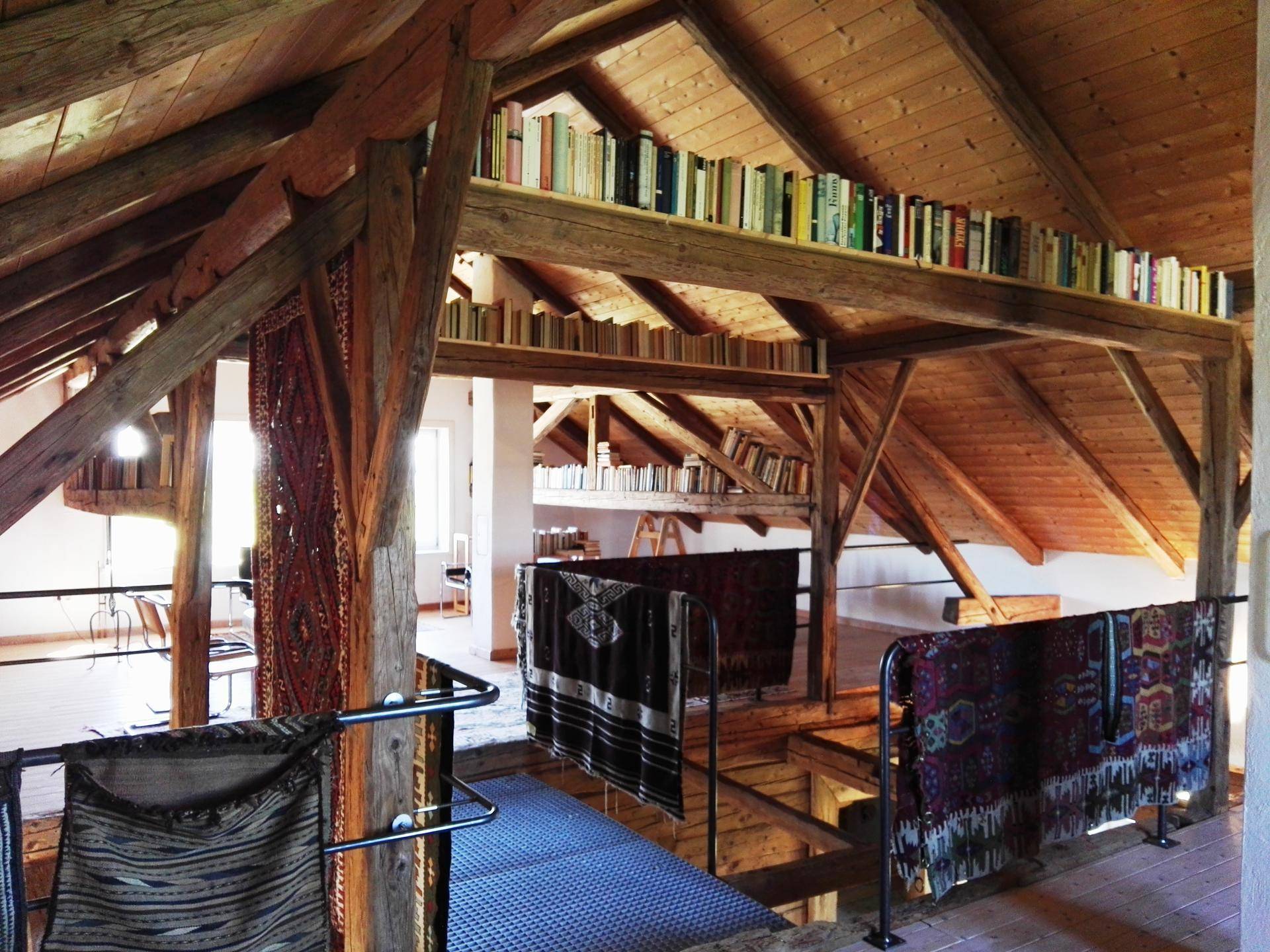 Offene Galerie im Dachgeschoss mit Bücherregalen, Holzbalken und Teppichen.