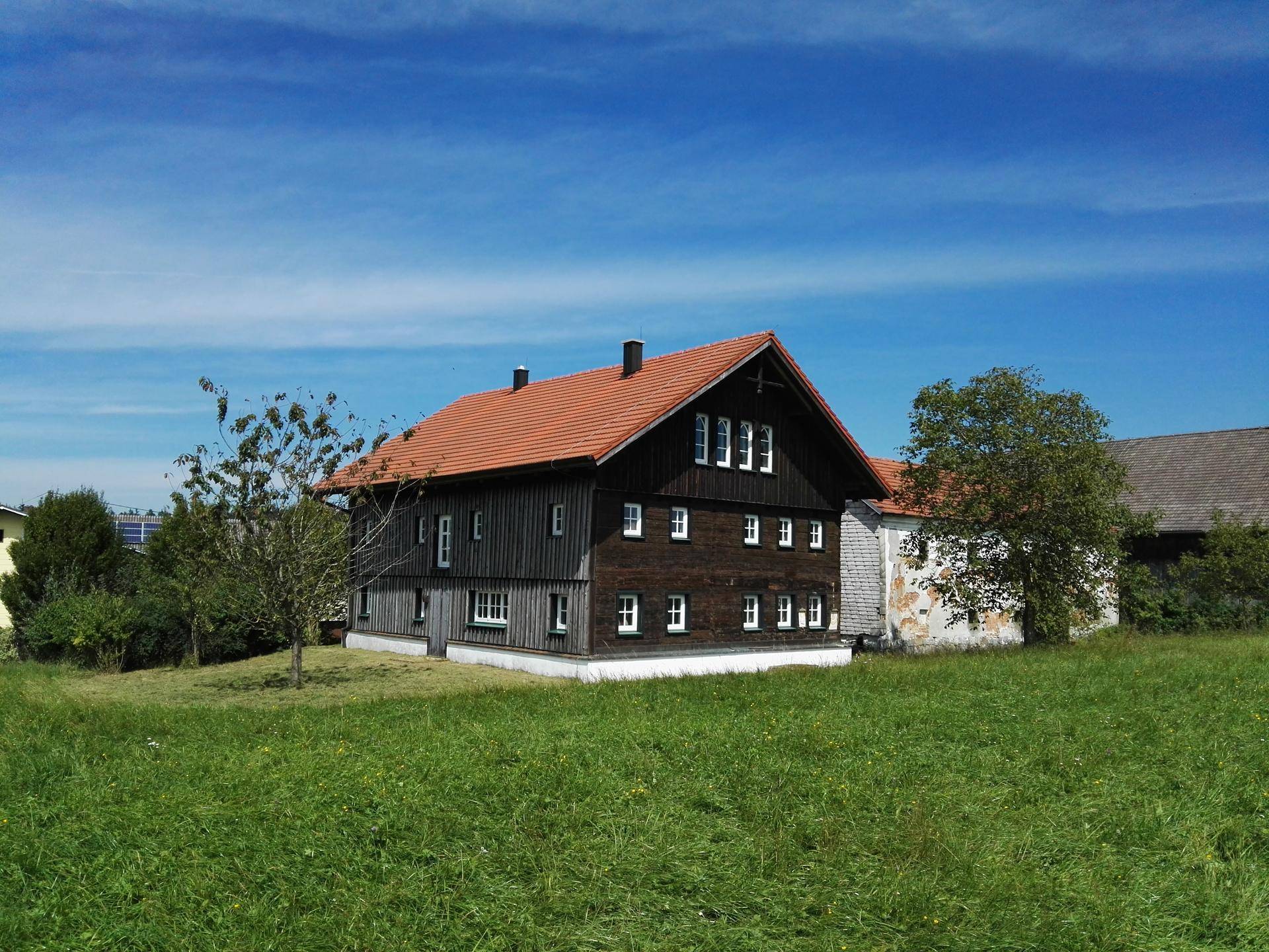 Großes Holzhaus mit rotem Ziegeldach und weitem Blick über die Landschaft.