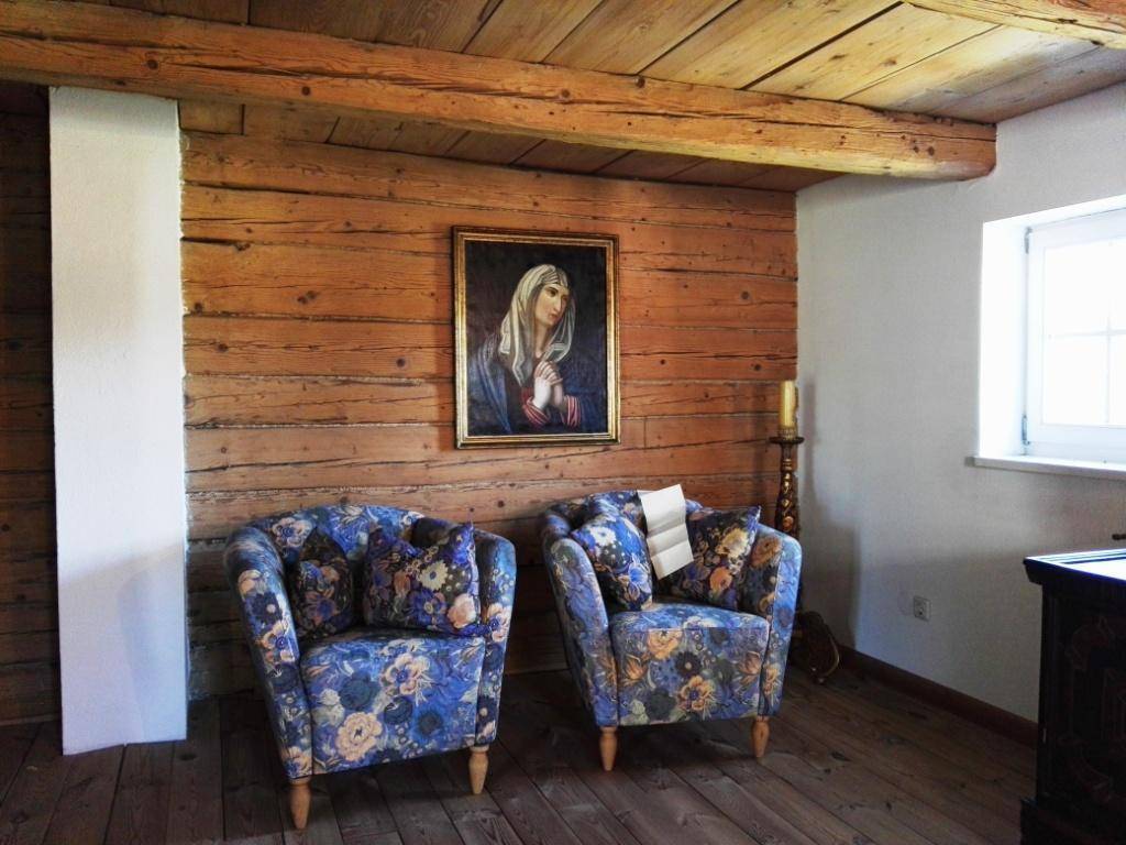 Gemütlicher Wohnbereich mit Holzwänden, floralen Sesseln und traditioneller Kunst.