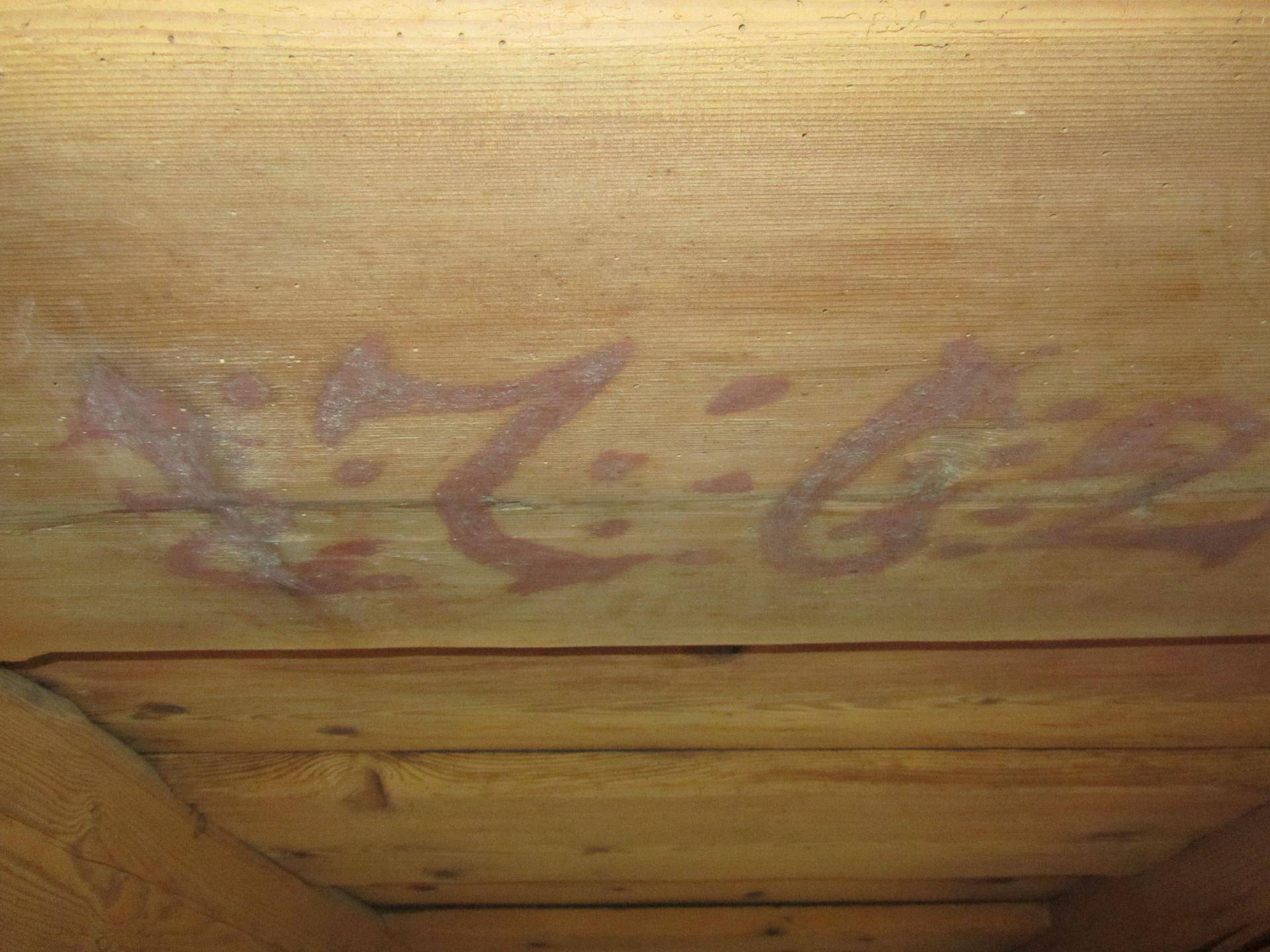 Nahaufnahme einer Holzdecke mit sichtbaren Maserungen und roten Markierungen.