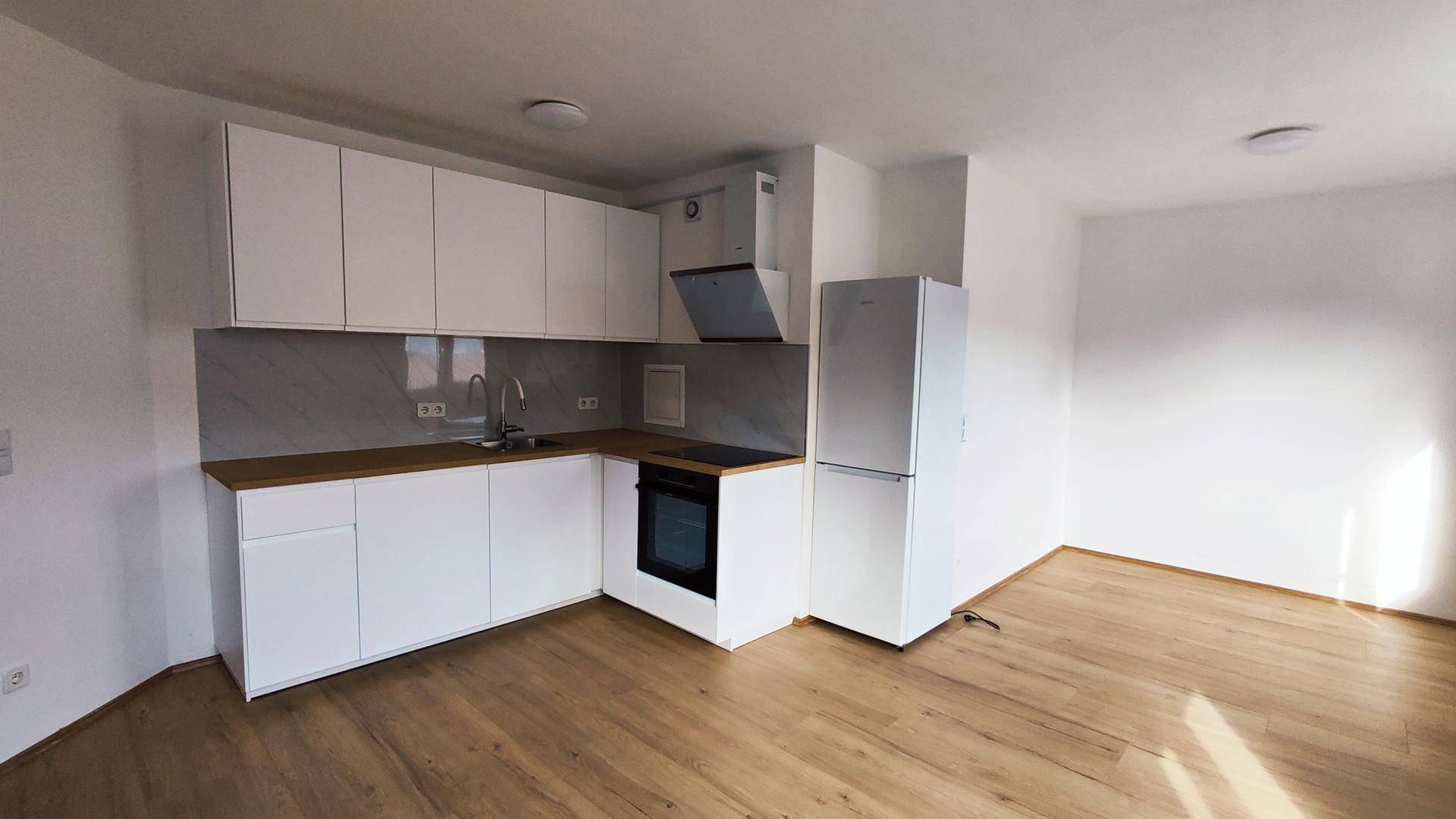 Helle, neuwertige Küche mit weißen Fronten, Holz-Arbeitsplatte und integrierten Geräten in offenem Raum.