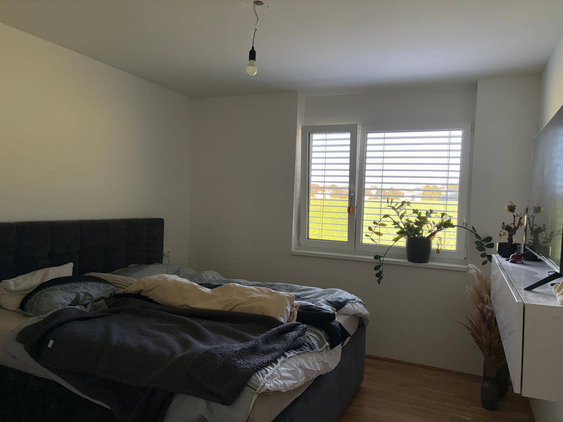 Gemütliches Schlafzimmer mit Holzboden, großem Bett und Ausblick auf die umliegende Natur.