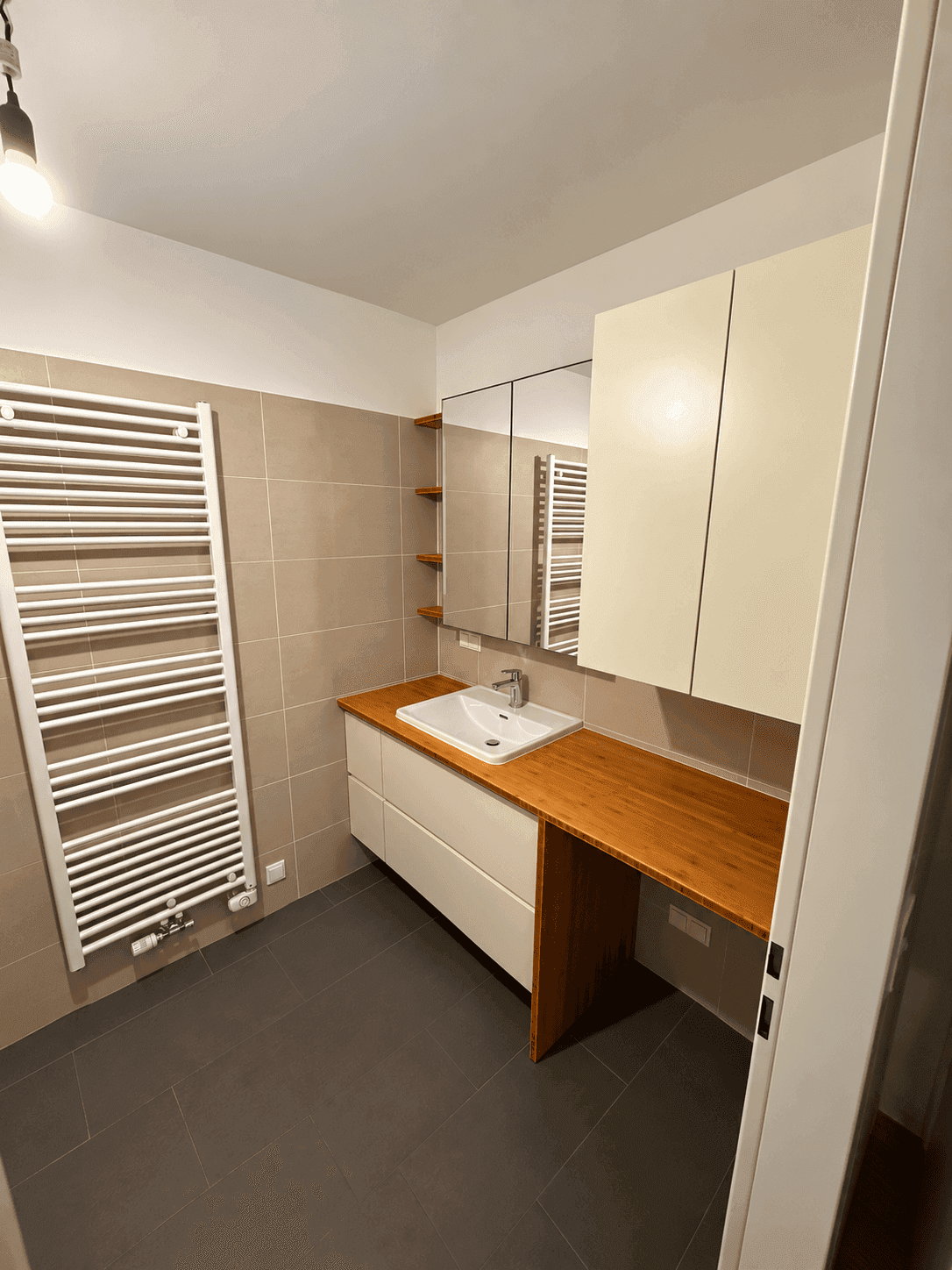 Modernes Badezimmer mit Einzelwaschbecken, Holzablage und beheiztem Handtuchhalter.