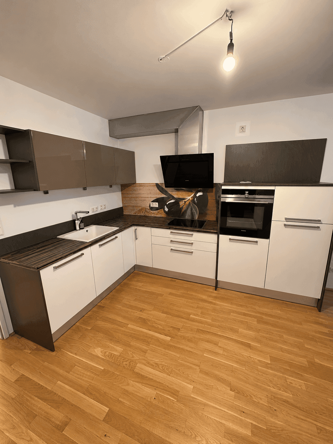 Moderne Einbauküche mit weißen und grauen Fronten, Induktionskochfeld und Backofen.