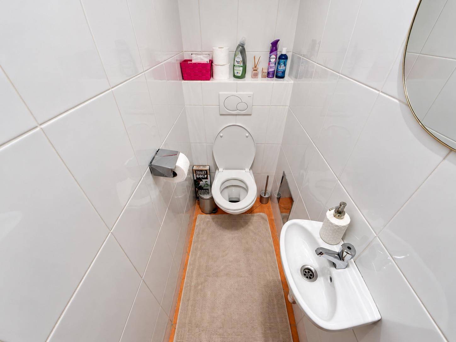Kleines separates WC mit Wand-WC, Handwaschbecken und weißen Fliesen.